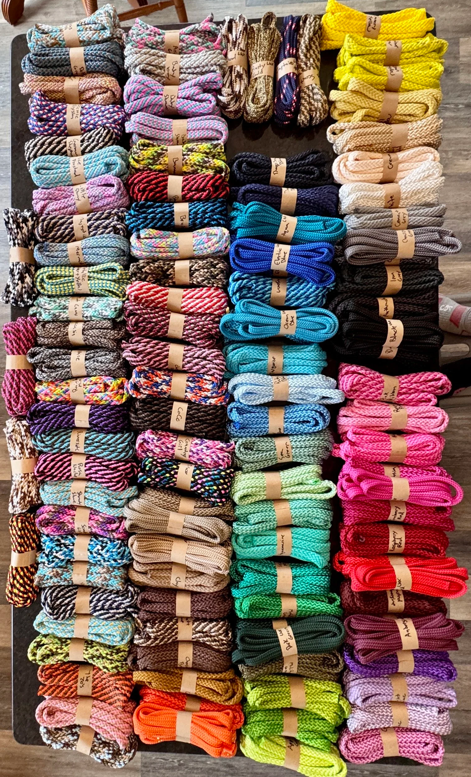 A colorful display of various braided rope laces arranged in rows on a table.