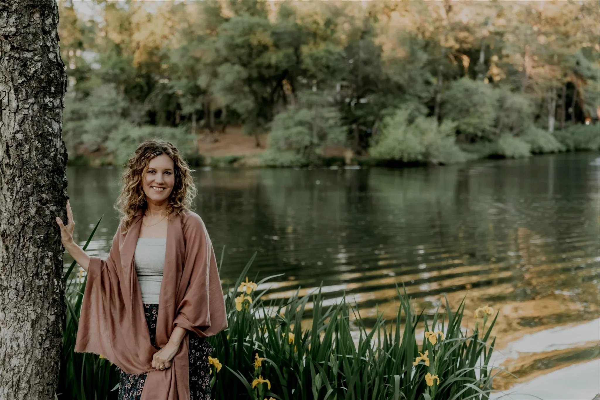 Rachael Courtier, psychotherapist in California, standing beside a quiet lake in a wooded setting