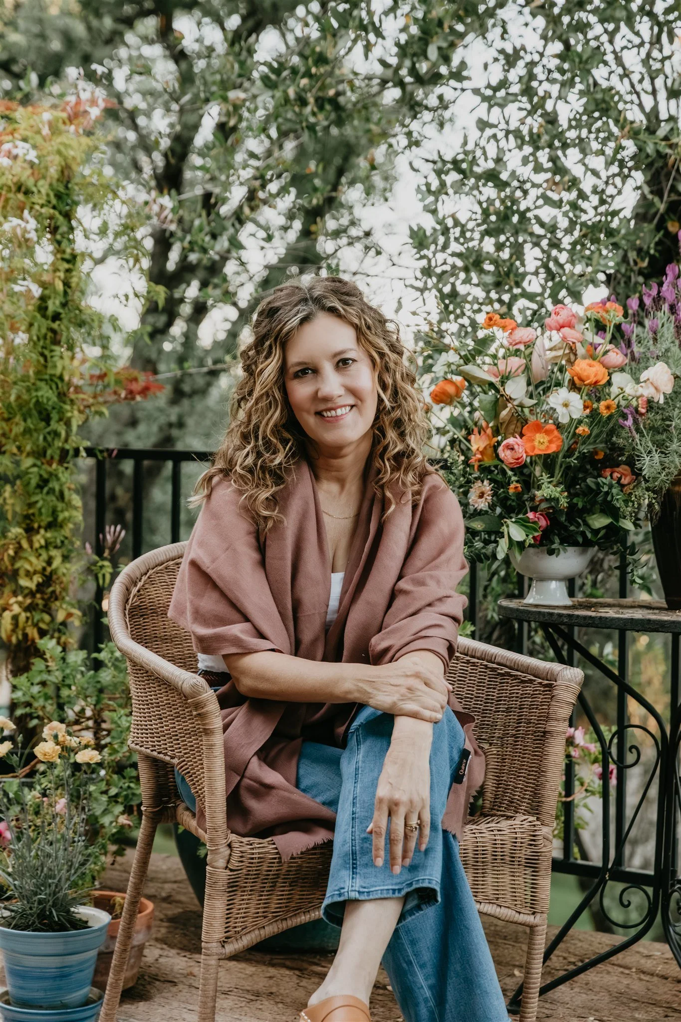 Rachael Courtier, IFS therapist, seated outdoors among flowers and greenery