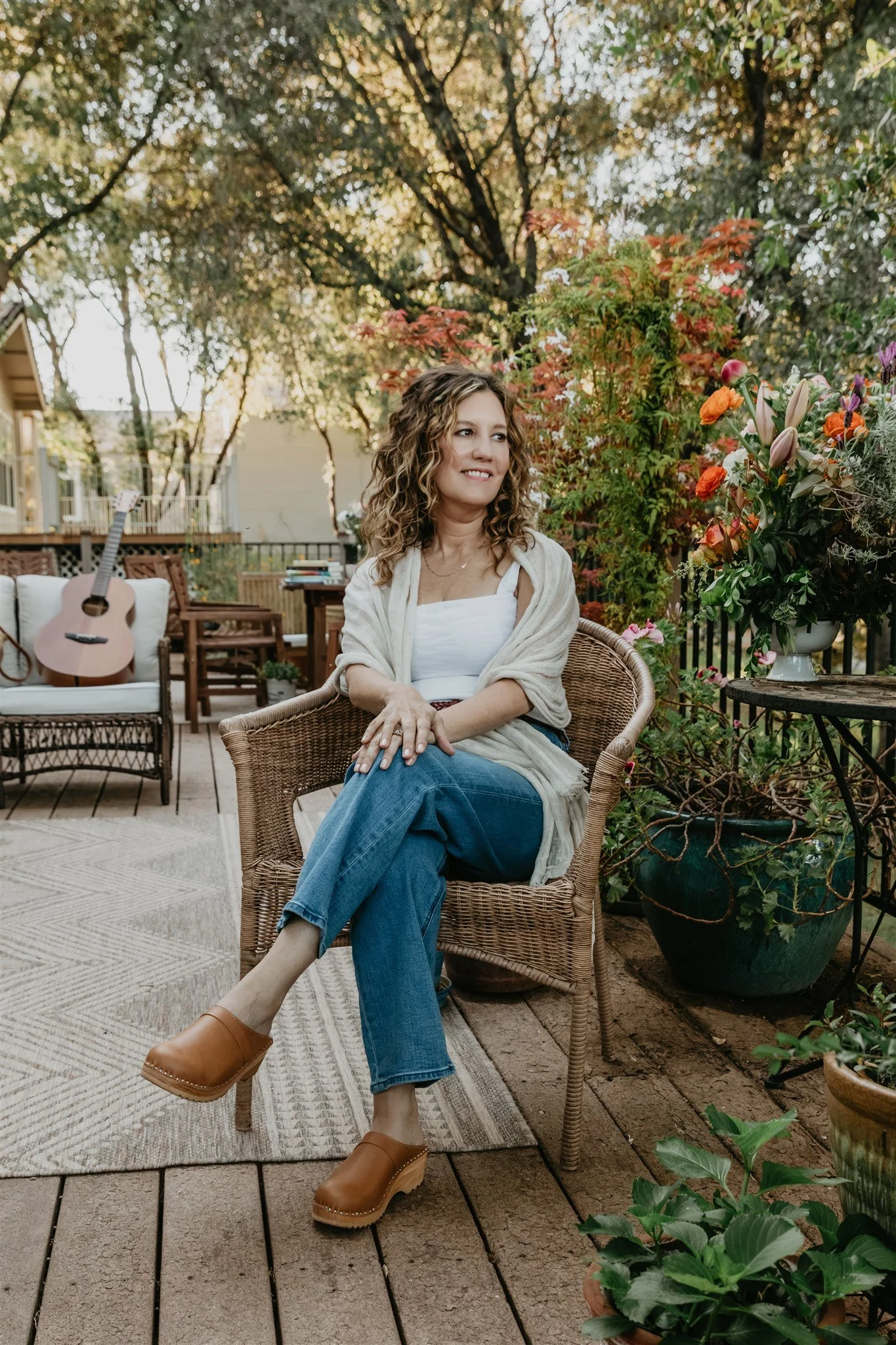 Rachael Courtier, attachment therapist, seated in a garden setting with flowers and natural light