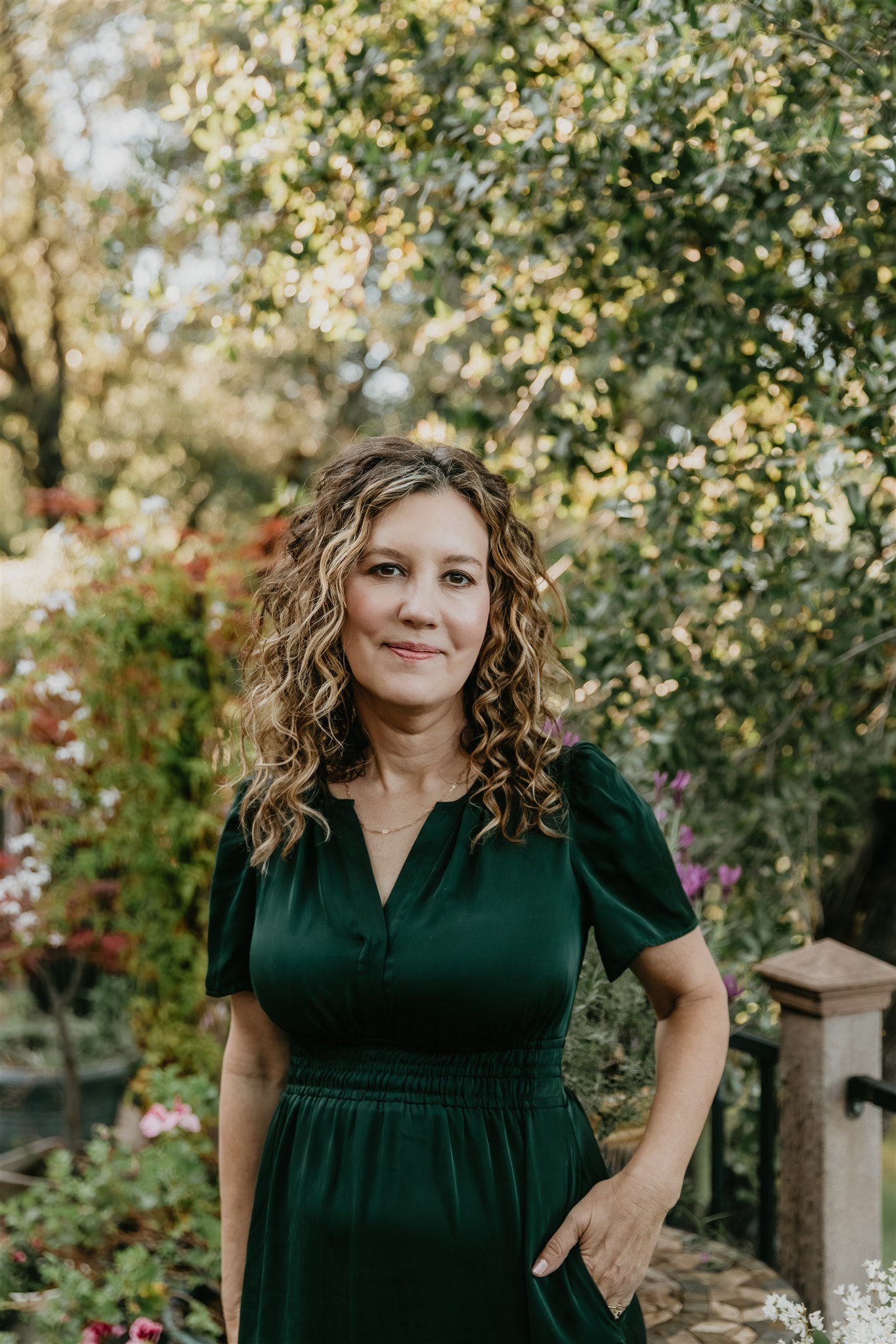 Rachael Courtier, attachment based therapist, in a warm outdoor portrait with soft greenery