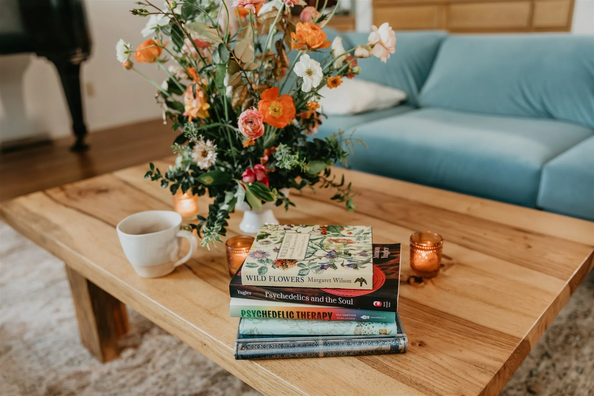 Therapy books, flowers, candles, and tea in a warm space for psychedelic assisted therapy