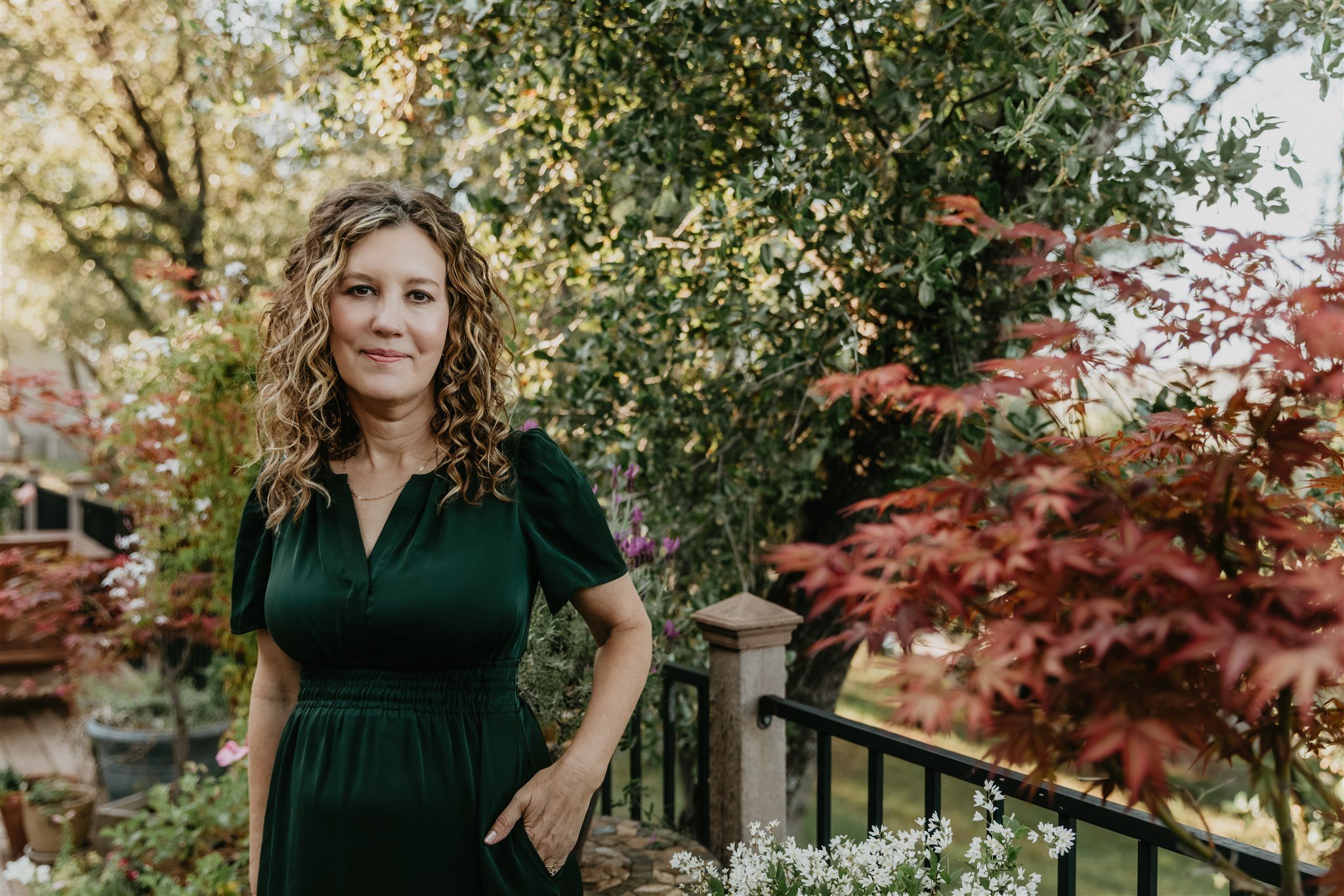 Rachael Courtier, attachment based therapist, in a warm outdoor portrait with soft greenery