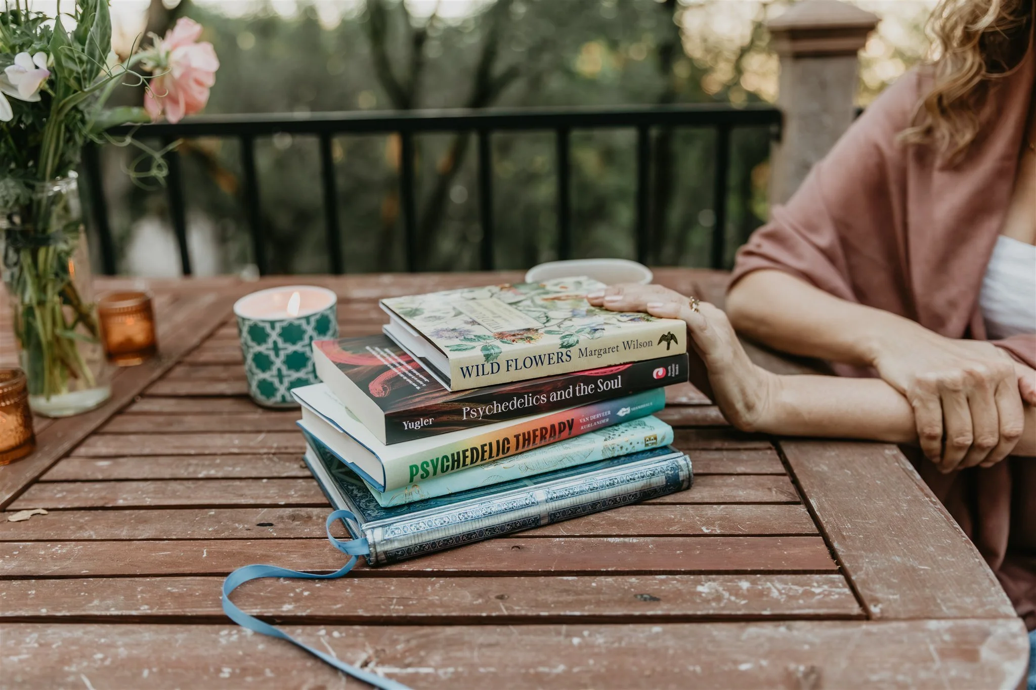 Books, flowers, candles, and tea on a table in Rachael Courtier’s therapy space