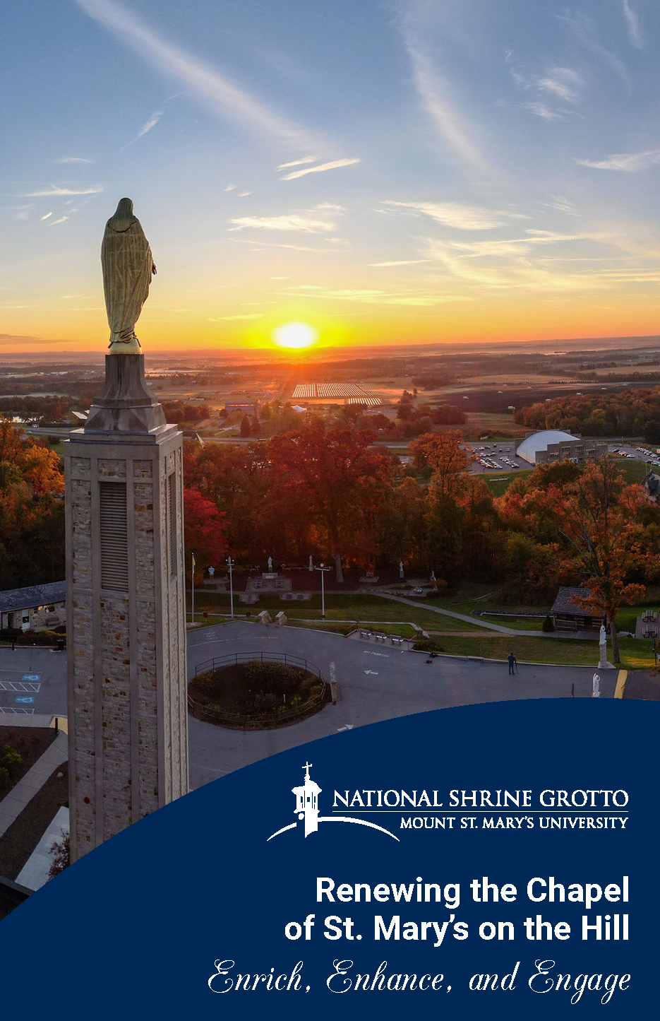 An aerial view of Mount St. Mary's University at sunset, featuring the statue of Mary atop the chapel, surrounded by autumn trees and open fields.