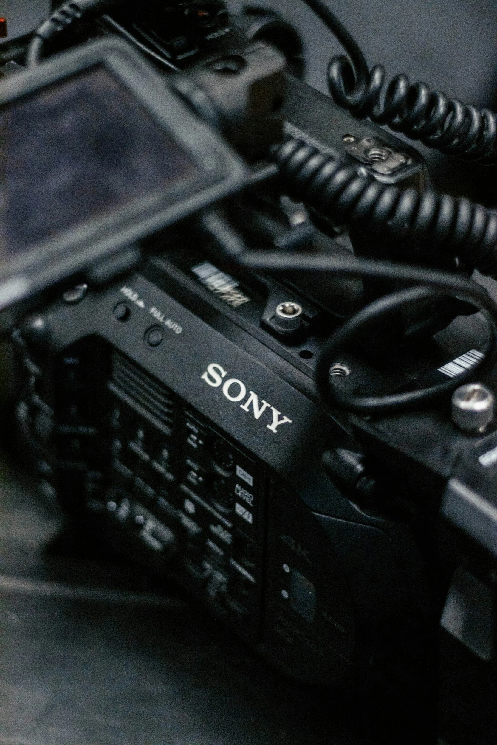 Close-up of a Sony camera with visible lens, focus on the brand label, surrounded by various cables and electronic components.
