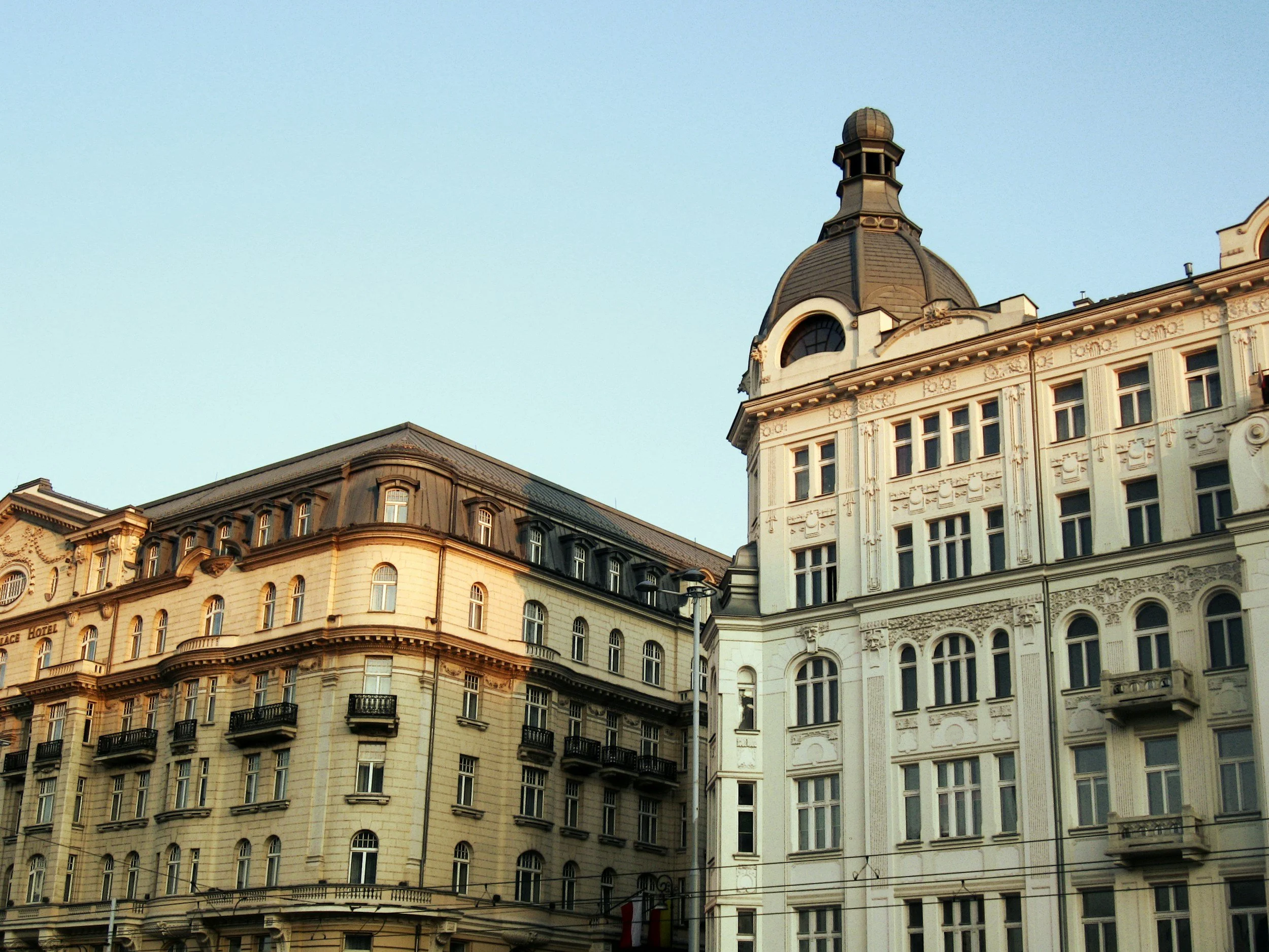 Vue en gros plan de bâtiments historiques avec des façades détaillées, des fenêtres ornées et un toit avec un dôme sur un ciel clair.