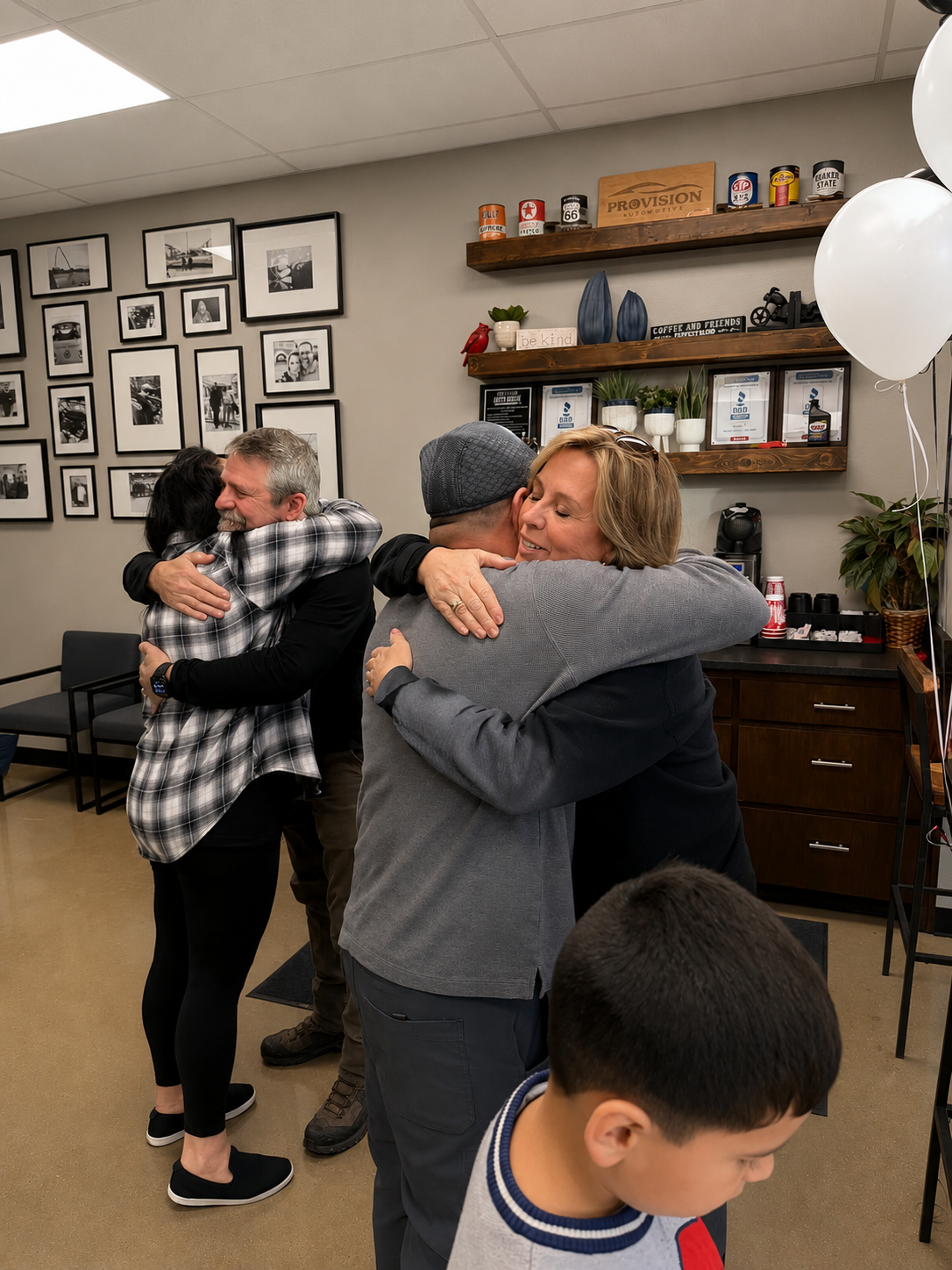 Three pairs of people hugging, in a room with framed photos on the wall and shelves with decorative items.