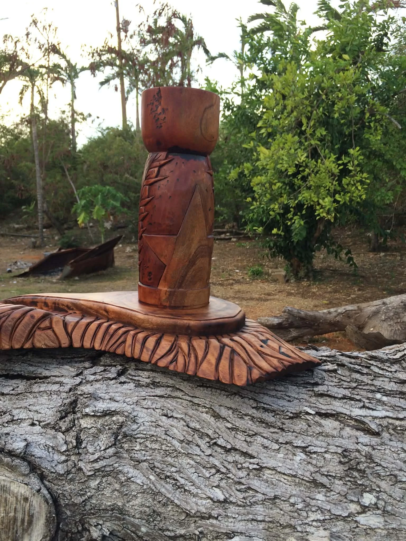 Image of a woodcarving of a Latte Stone with the CNMI flag motifs decorated throughout the piece.