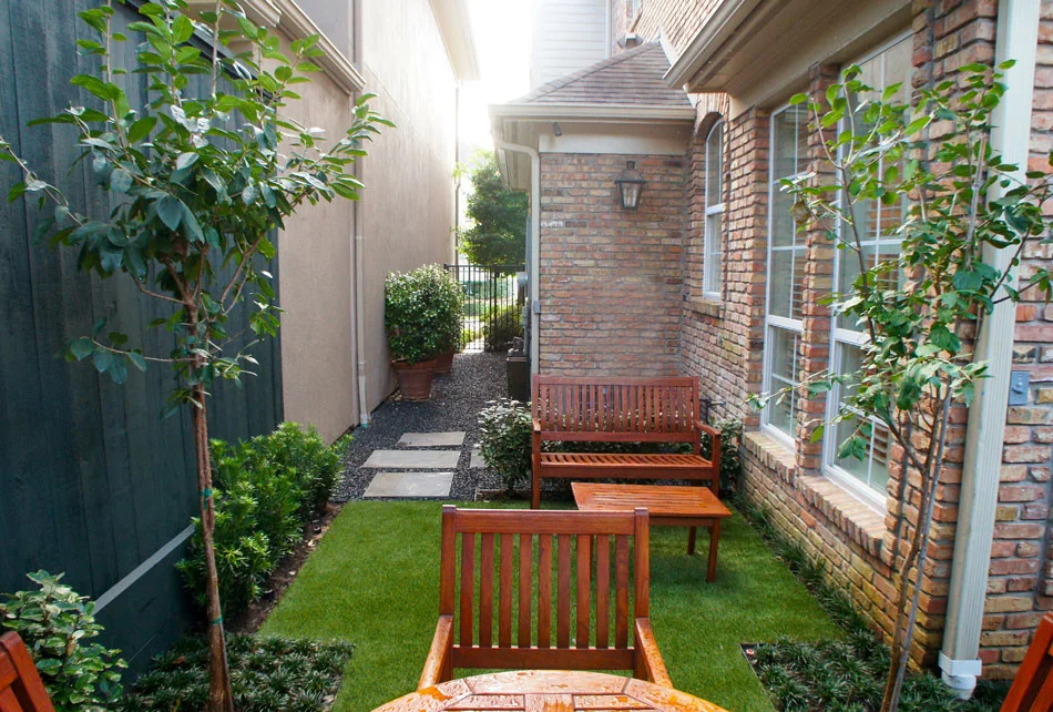 From the side gate, rectangular stepping pads lead to a secluded outdoor dining area and a perfectly shaped artificial lawn is framed by Japanese Yews, Dwarf Mondo Grass and Blackstar Gravel.
