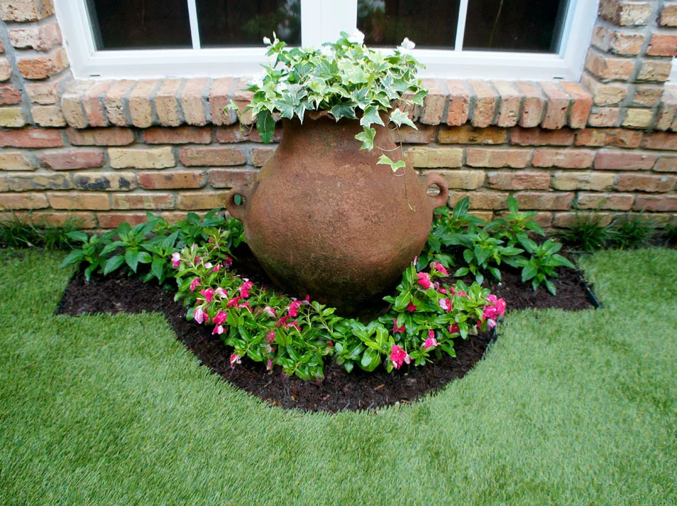 This repurposed planter has become a garden focal point. It holds Variegated English Ivy and White Vinca and is surrounded by hot, red-pink Vinca and flanked by red Penta, which are about to bloom as well.