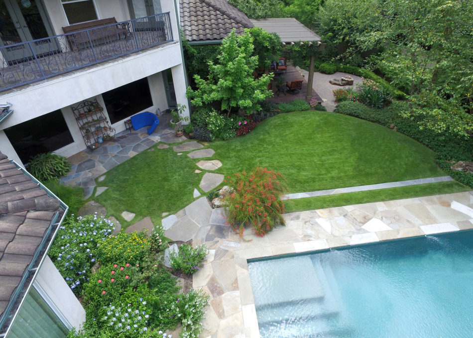 The use of circles and ellipses in this space give a bold, expressive sense of unity that cohesively connects the pool, house, and raised deck, creating a sense of oneness throughout. Flagstone was used to deconstruct the sharp edge of the pool whic…