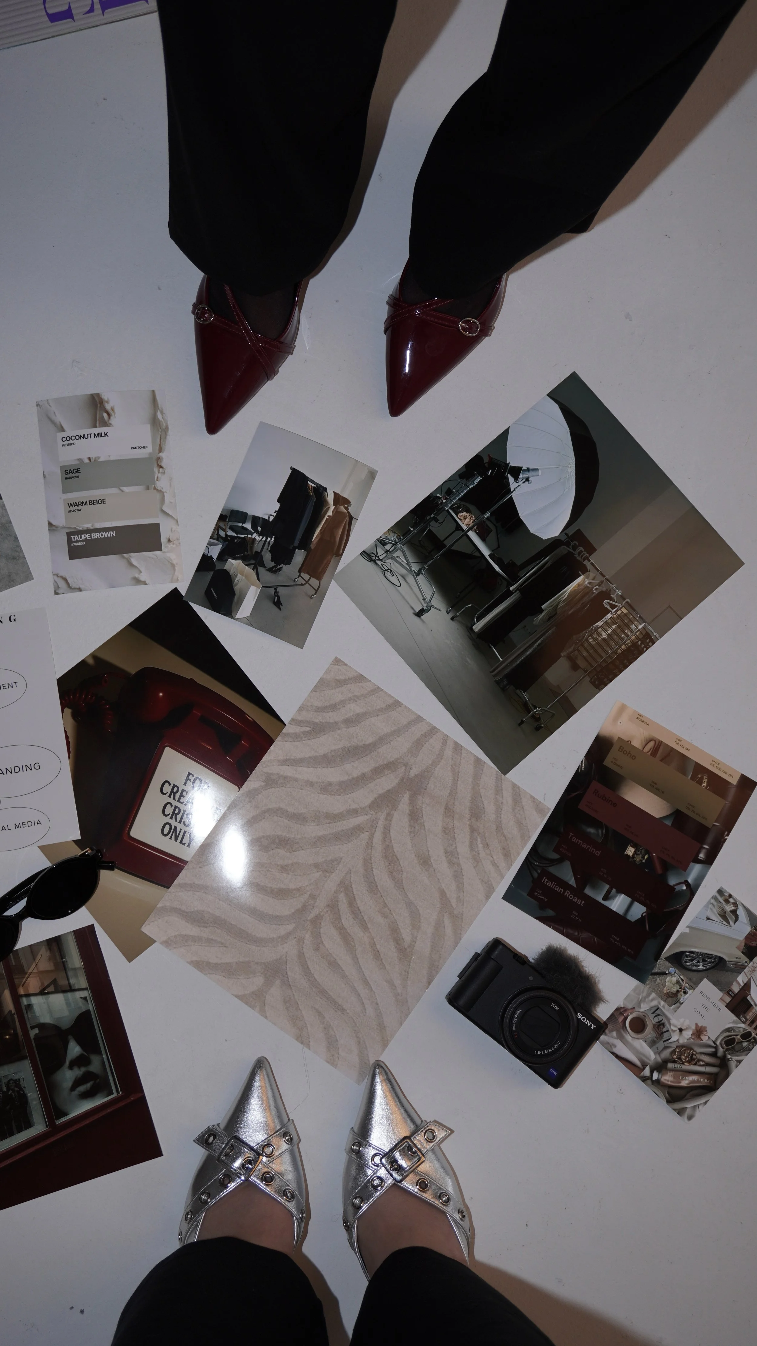 The photo shows a person's feet in shiny silver pointed-toe shoes with buckles, standing over scattered printed photos, color swatches, and fashion accessories on the floor.
