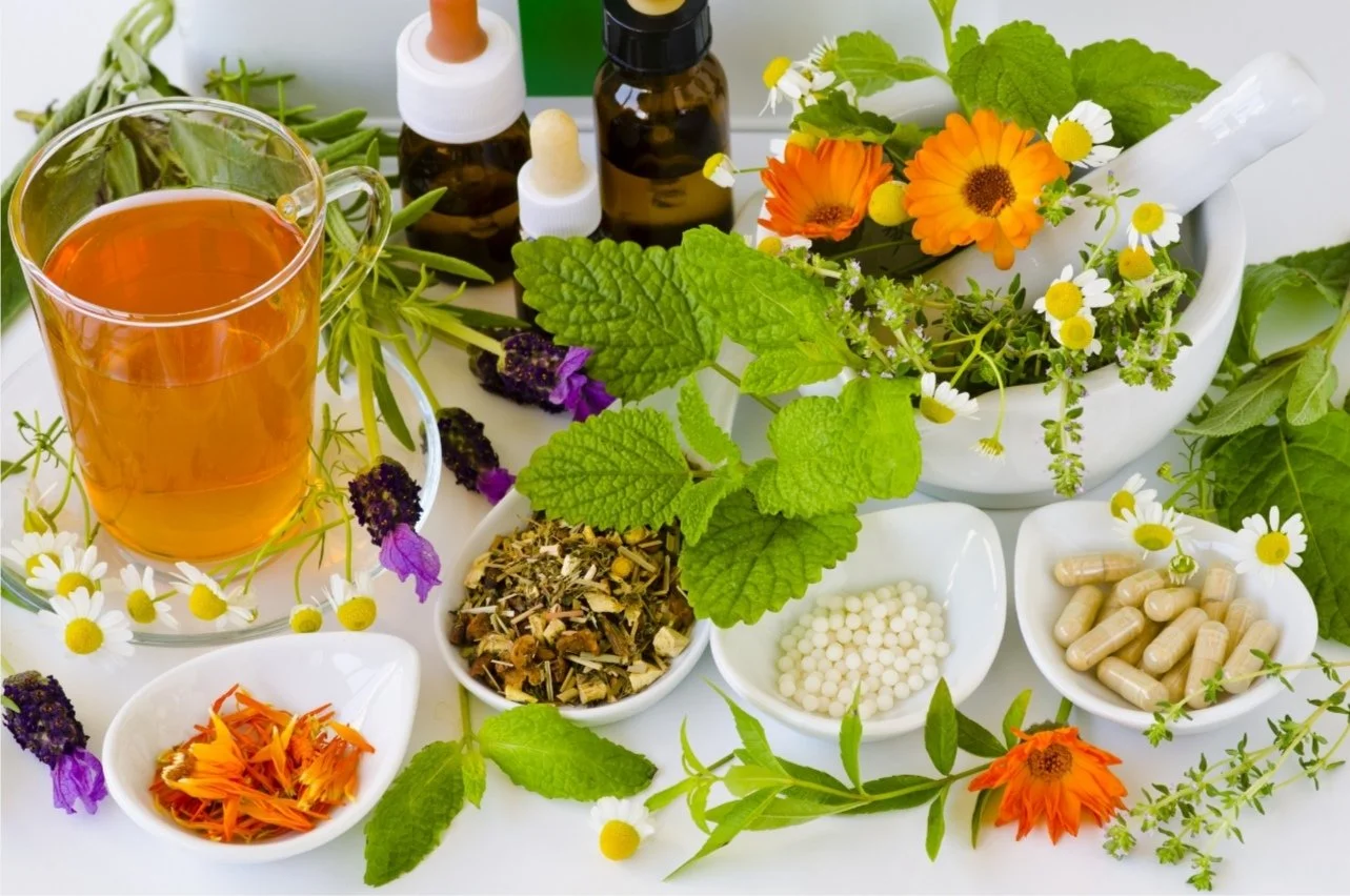Ingrédients naturels pour remèdes maison, comprenant des fleurs, des feuilles, des capsules, des huiles essentielles, et une boisson à base de plantes dans un contexte de médecine douce.