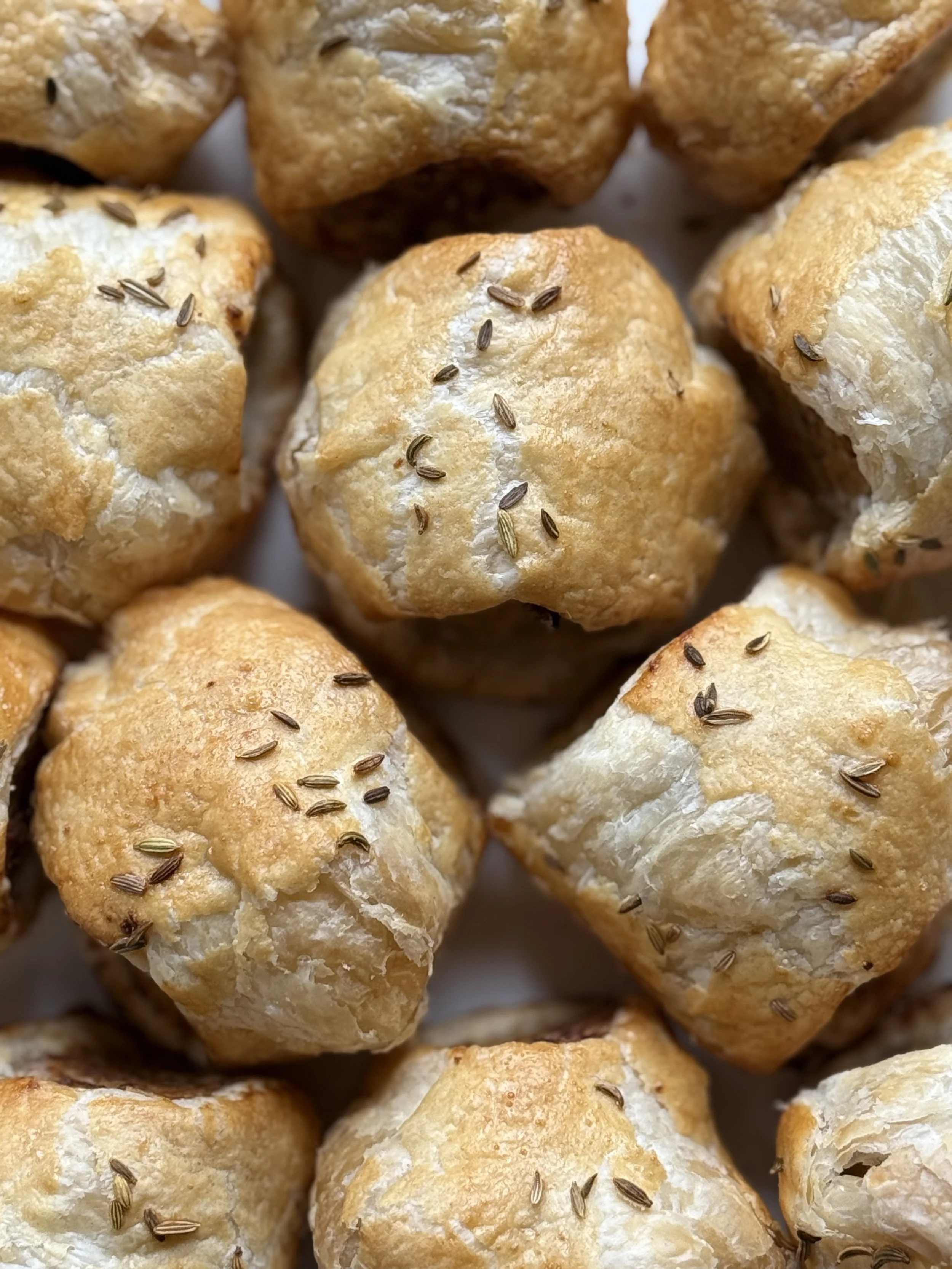 Close-up of freshly baked bread rolls topped with caraway seeds.