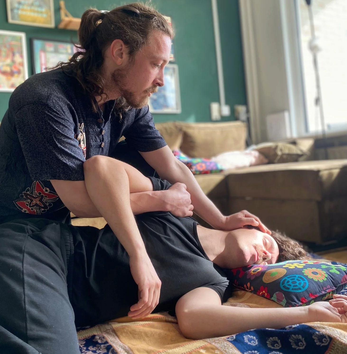 Behandelaar geeft een ontspannende shiatsu-geïnspireerde lichaamswerksessie in een rustige huiselijke omgeving.