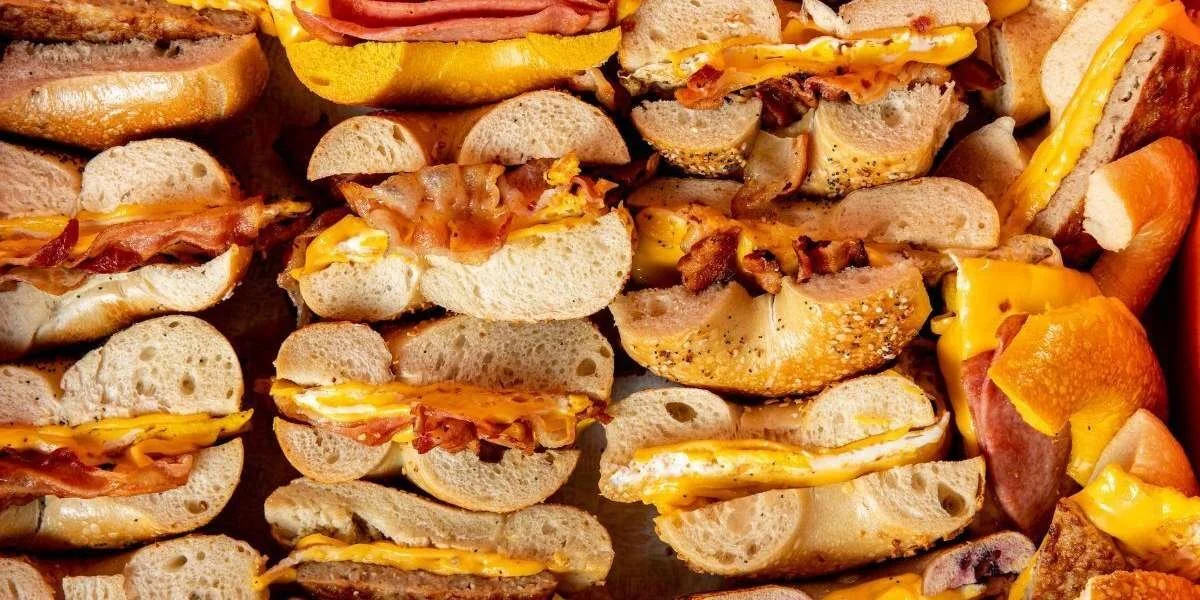 Multiple bacon, egg, and cheese breakfast sandwiches on small hoagie rolls.