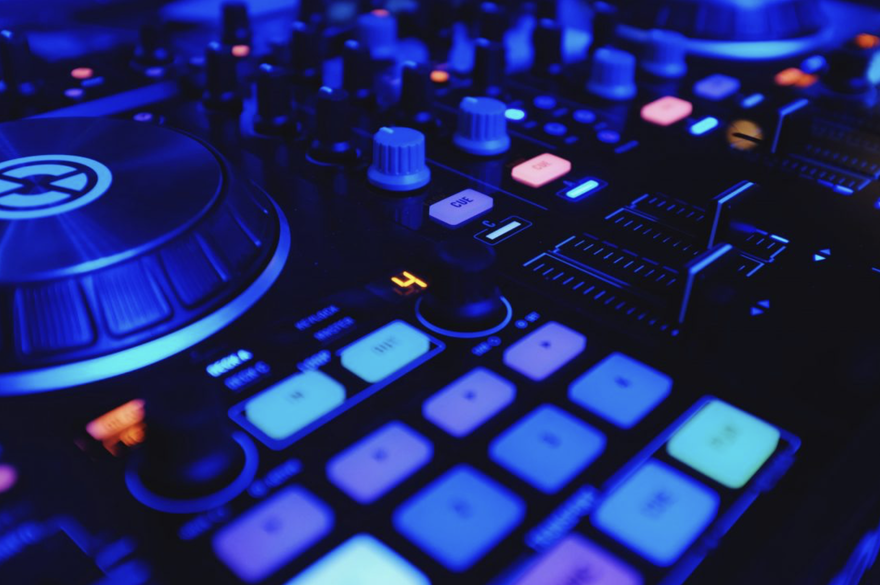 Close-up of a DJ controller with illuminated buttons and knobs in blue and colorful hues, showing a large jog wheel and various control sliders.
