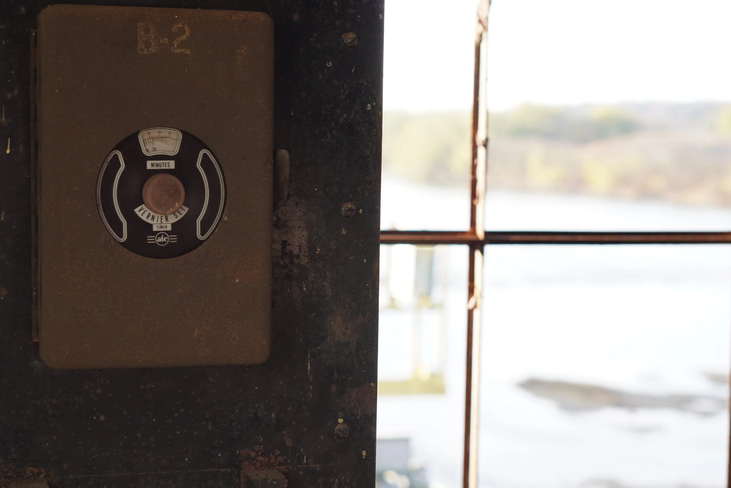 Close-up of a vintage timer labeled 'Vernier Set' with a rusty knob, mounted on a weathered metal surface with chipped paint.