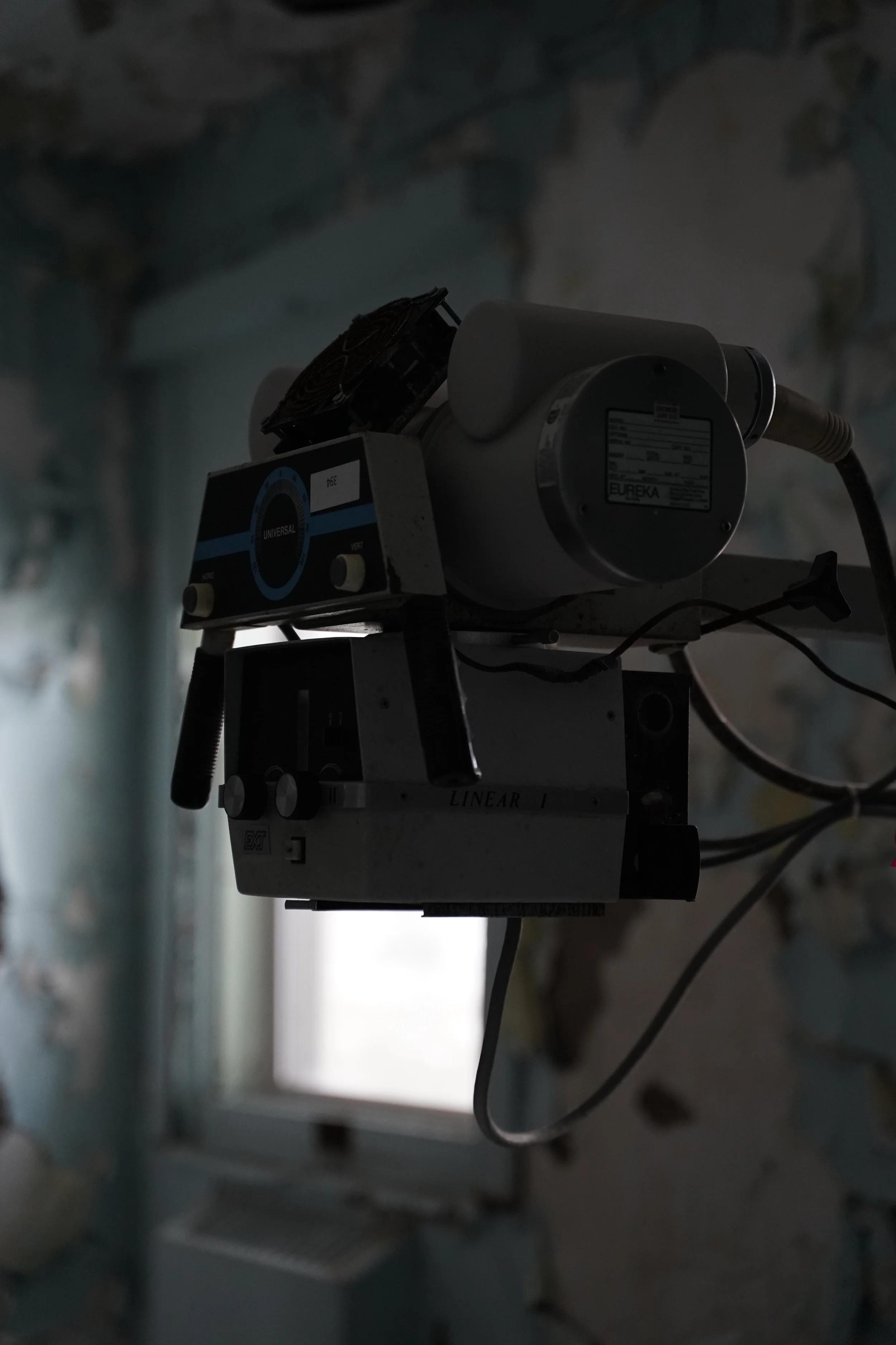 Close-up photo of a scientific instrument or device mounted on a wall or stand in a laboratory or industrial setting, with cables connected to it.
