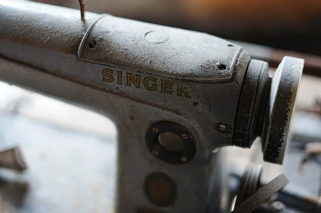 Close-up of an old Singer sewing machine with a dusty, weathered surface.