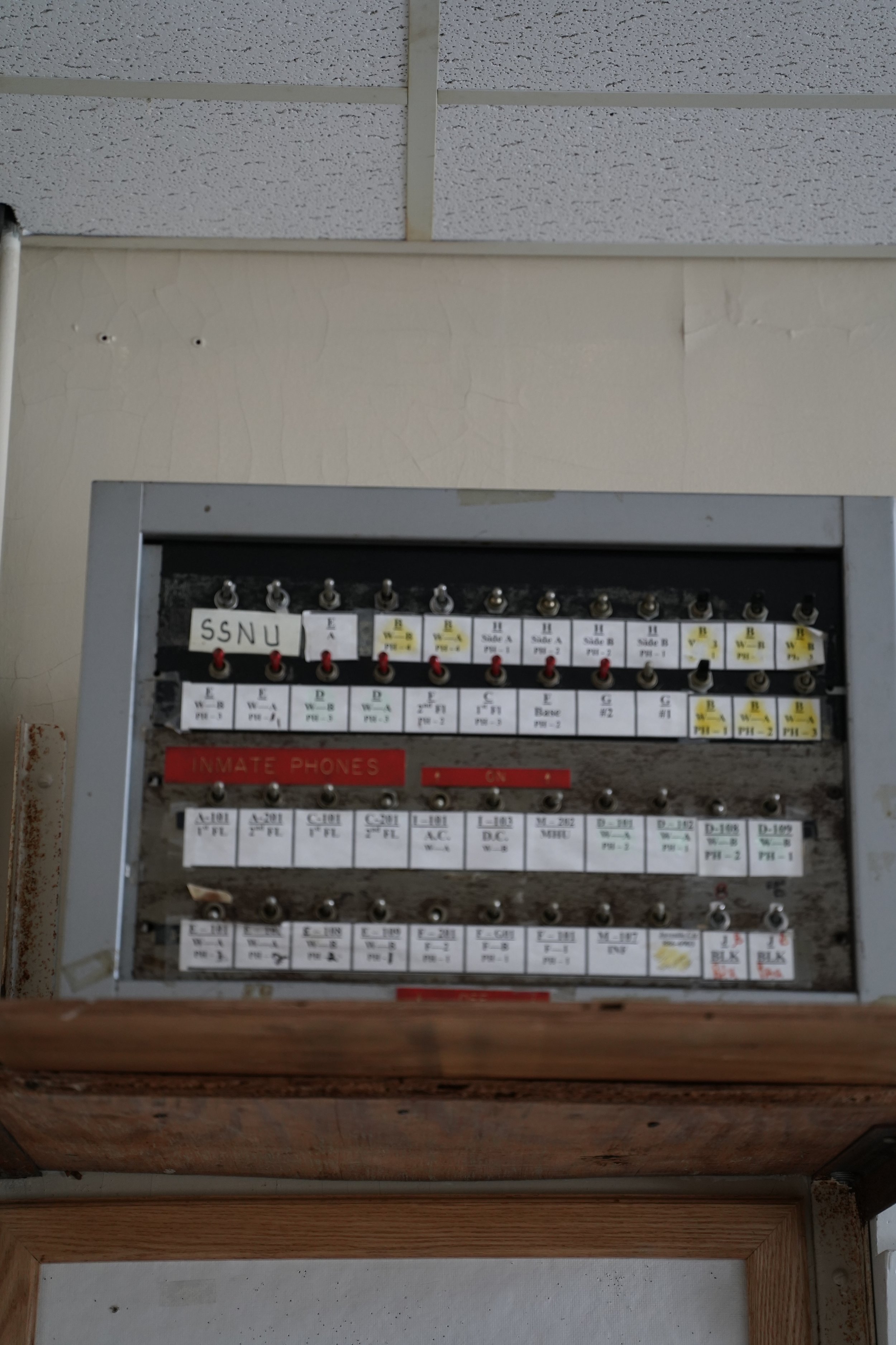 An electrical panel with fuses and switches, labeled with various codes and descriptions. The panel has a red label that says 'INMATE PHONES'.