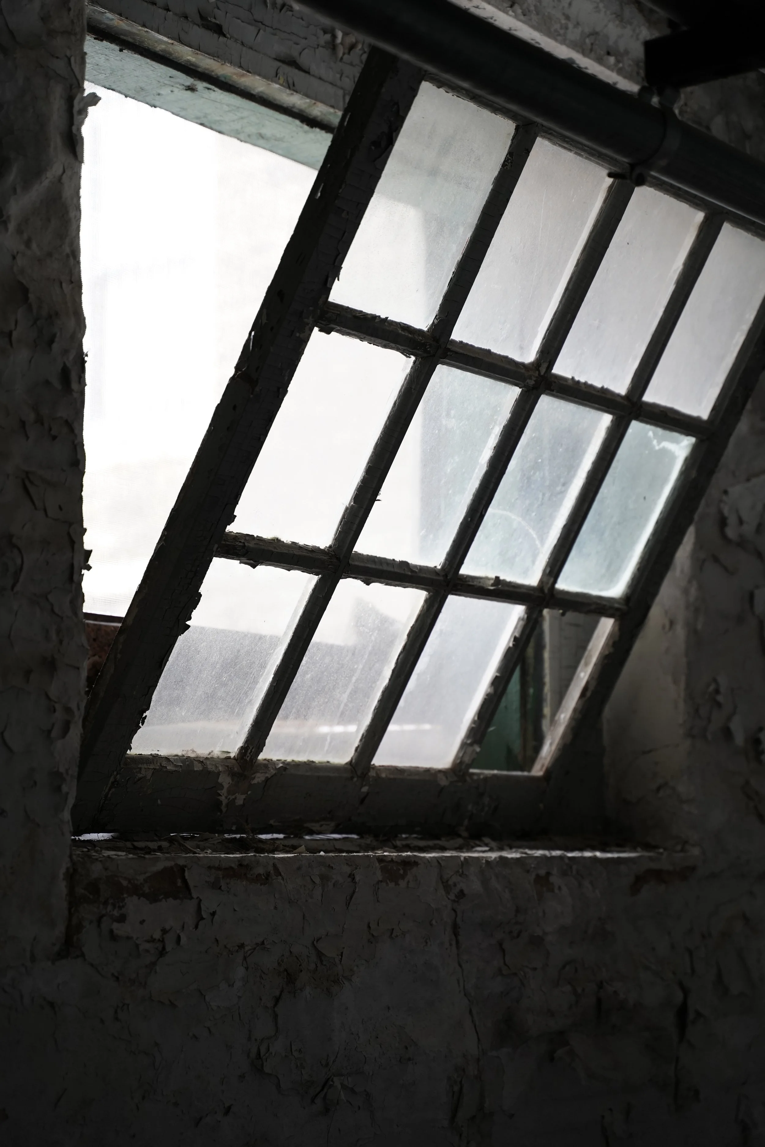 A view of a skylight window with bars, set in a rough, textured wall, allowing natural light to come through.