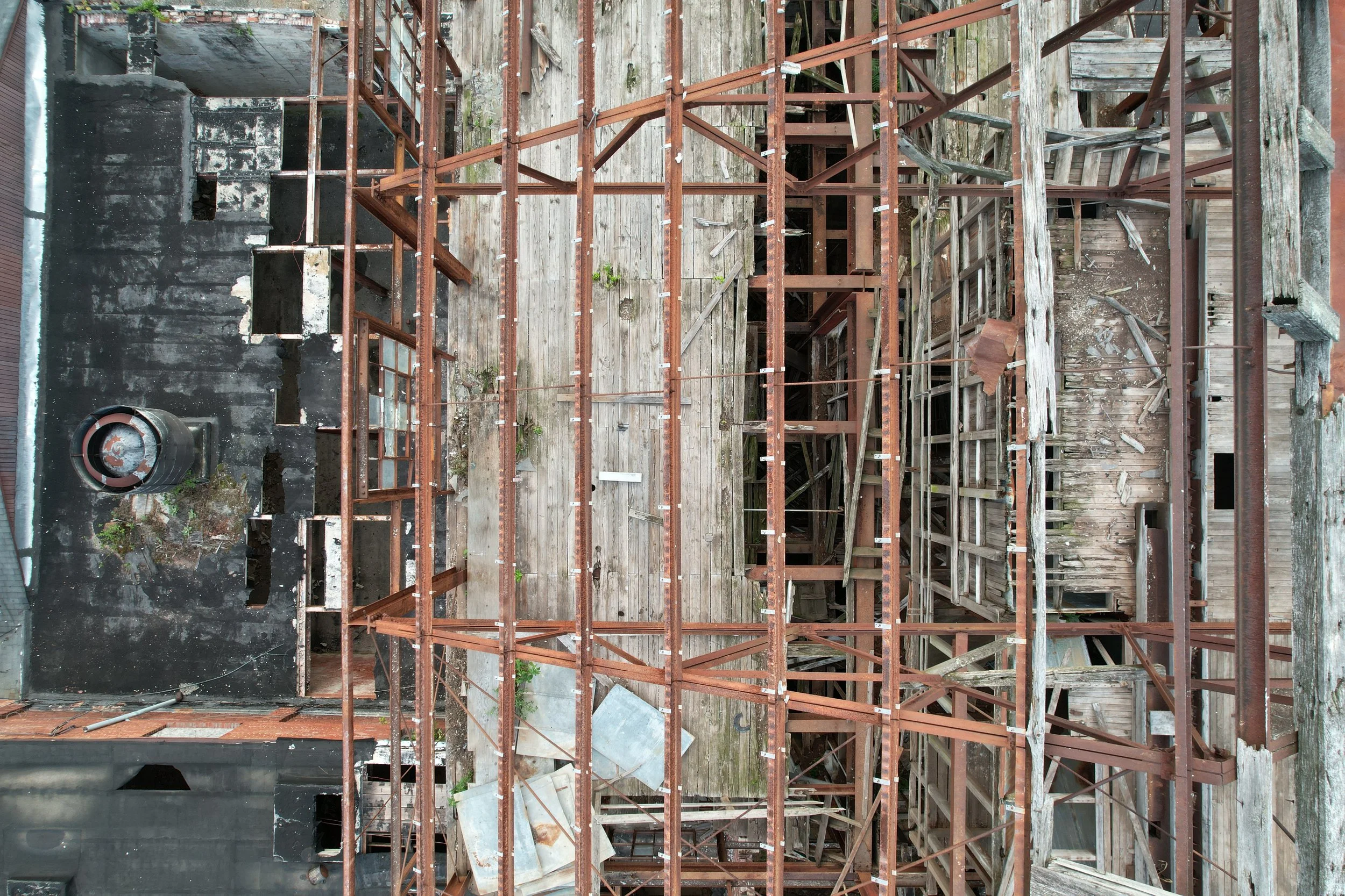 A view of a building under construction with exposed wooden and metal framework, scaffolding, and partially demolished walls.