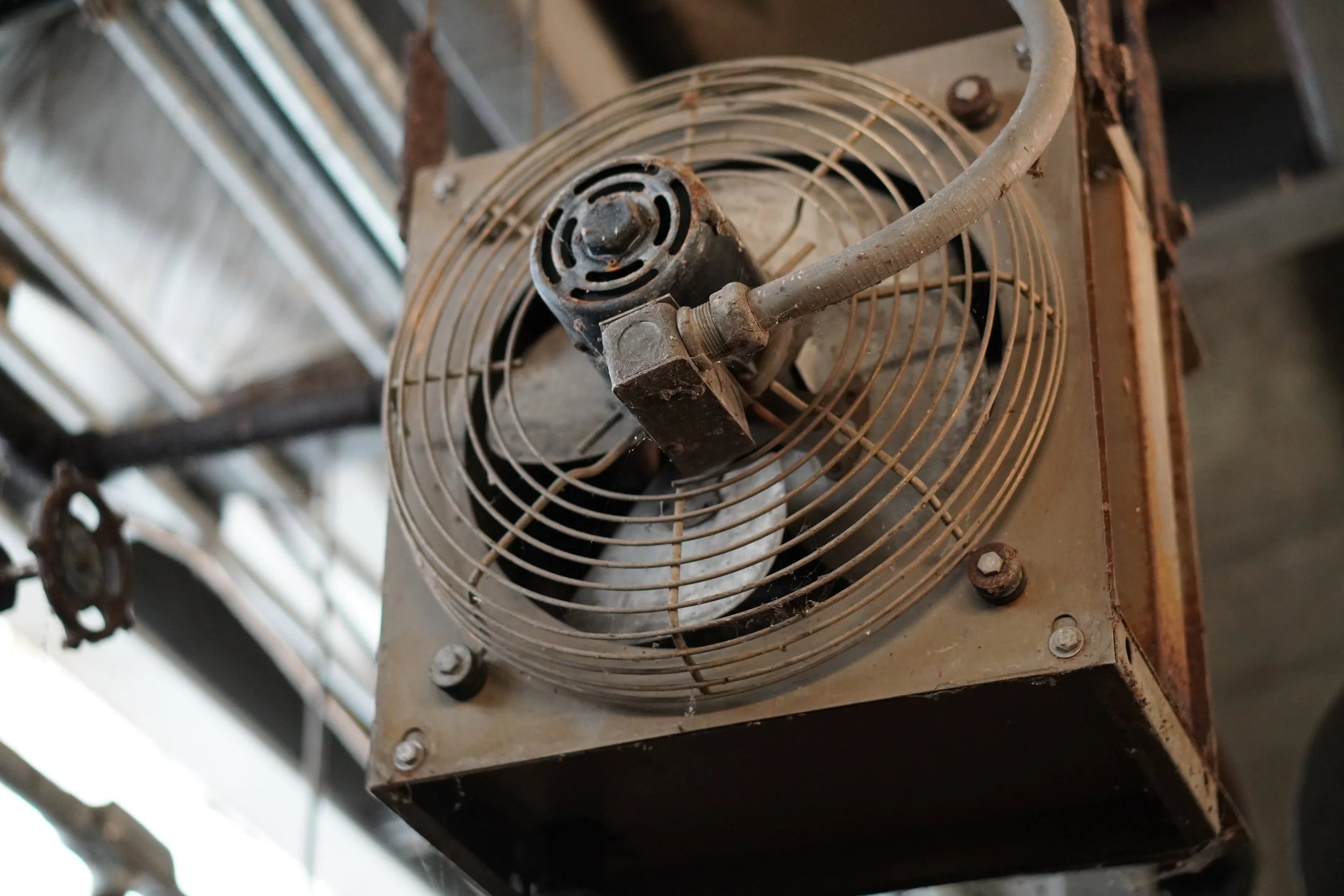 An old, rusty electric fan mounted on a metal surface.