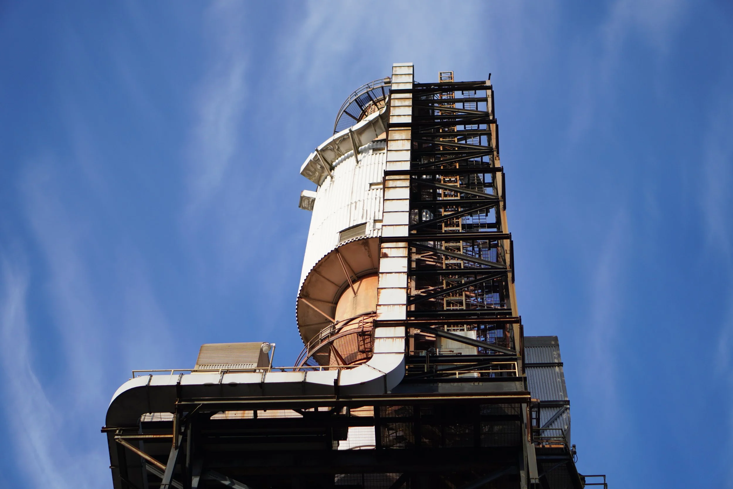 Close-up of an industrial water slide structure with rusted metal framework against a blue sky.