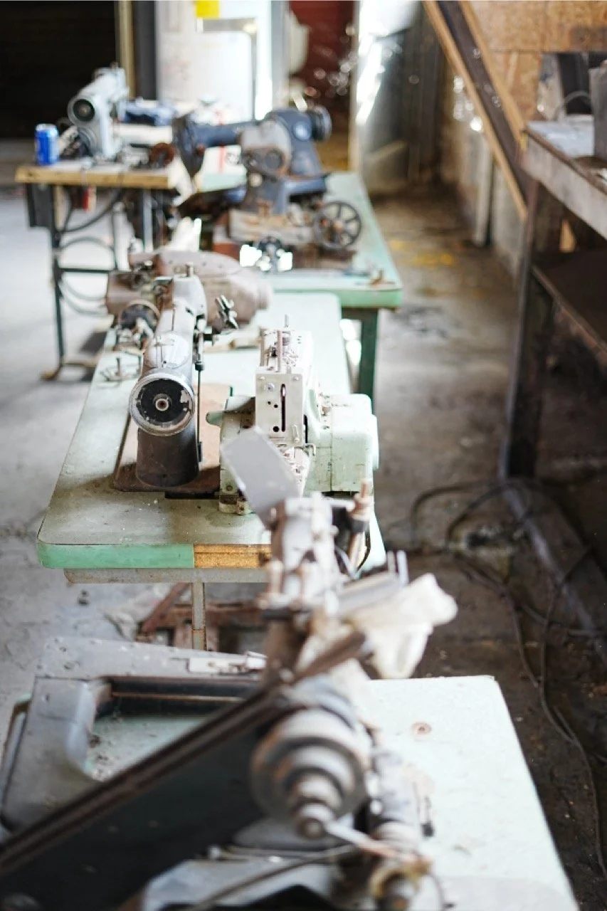 Old, rusty sewing or mechanical devices on workbenches in a workshop.