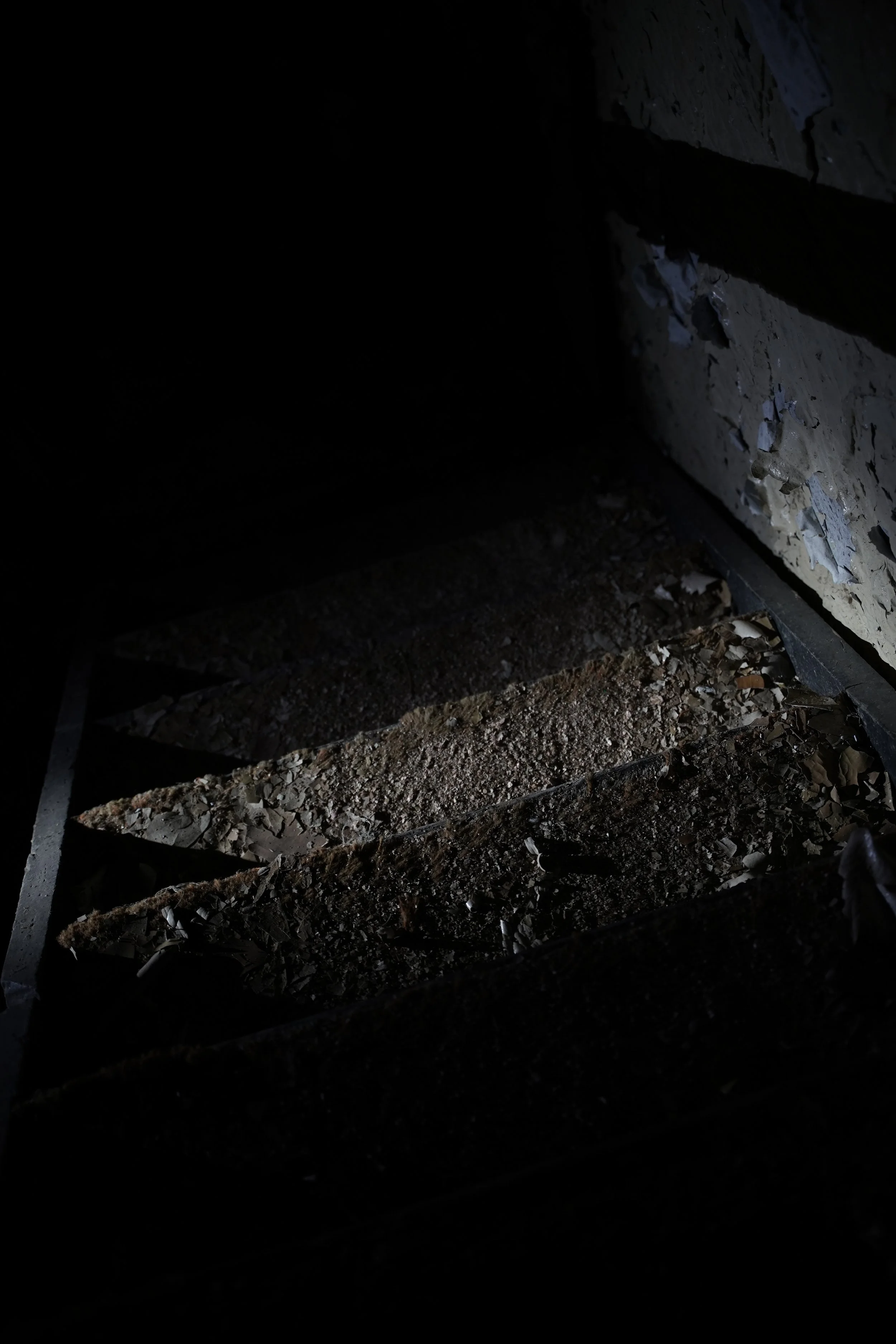 Close-up of wooden planks and debris on the ground, with shadows and minimal light illuminating the scene.
