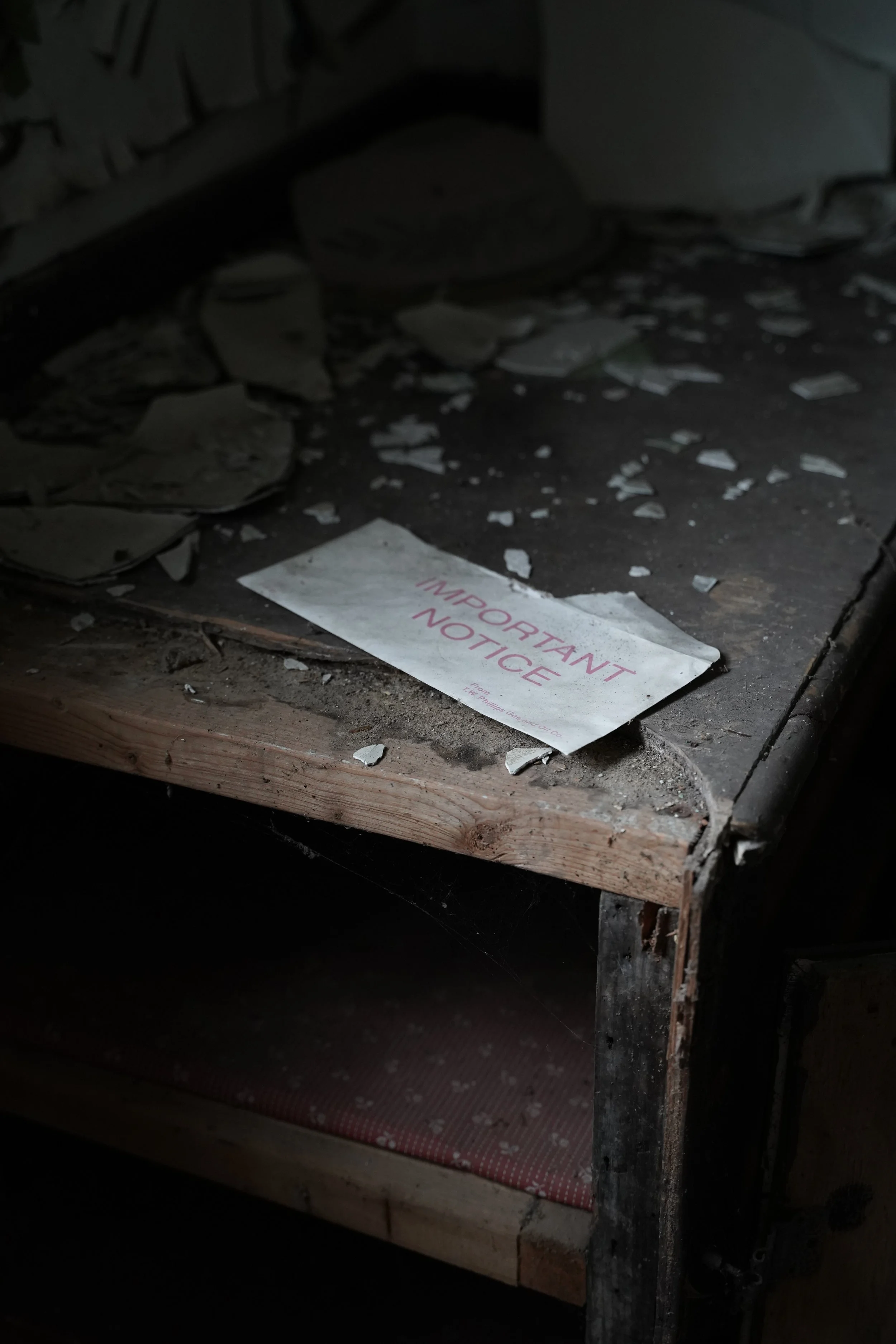 A dimly lit wooden bunk bed with a red and white polka dot mattress, a pile of broken tiles and rubble underneath, and a notice on the floor that reads 'IMPORTANT NOTICE'.