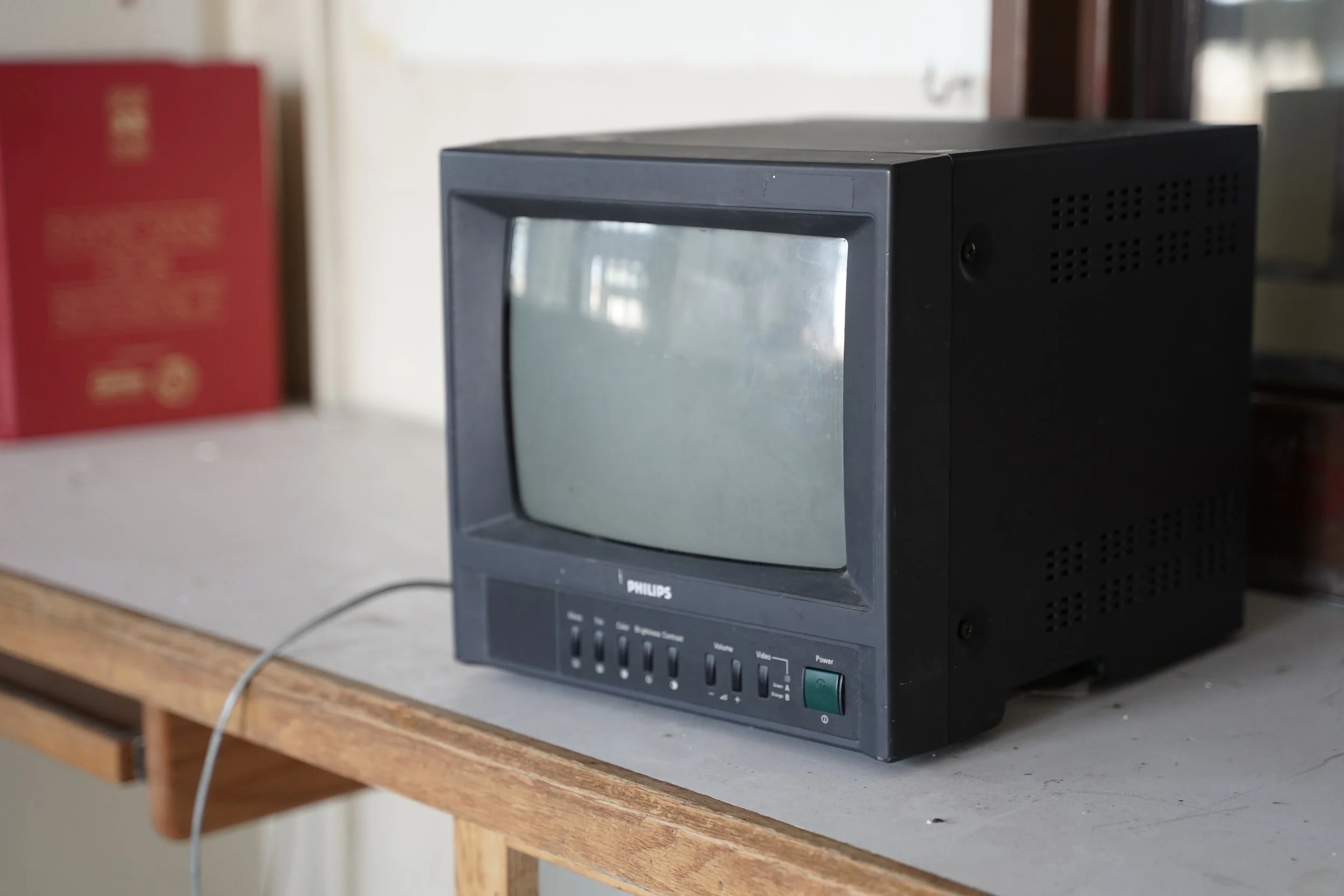 A vintage black Phillips television with a small screen is placed on a wooden table.