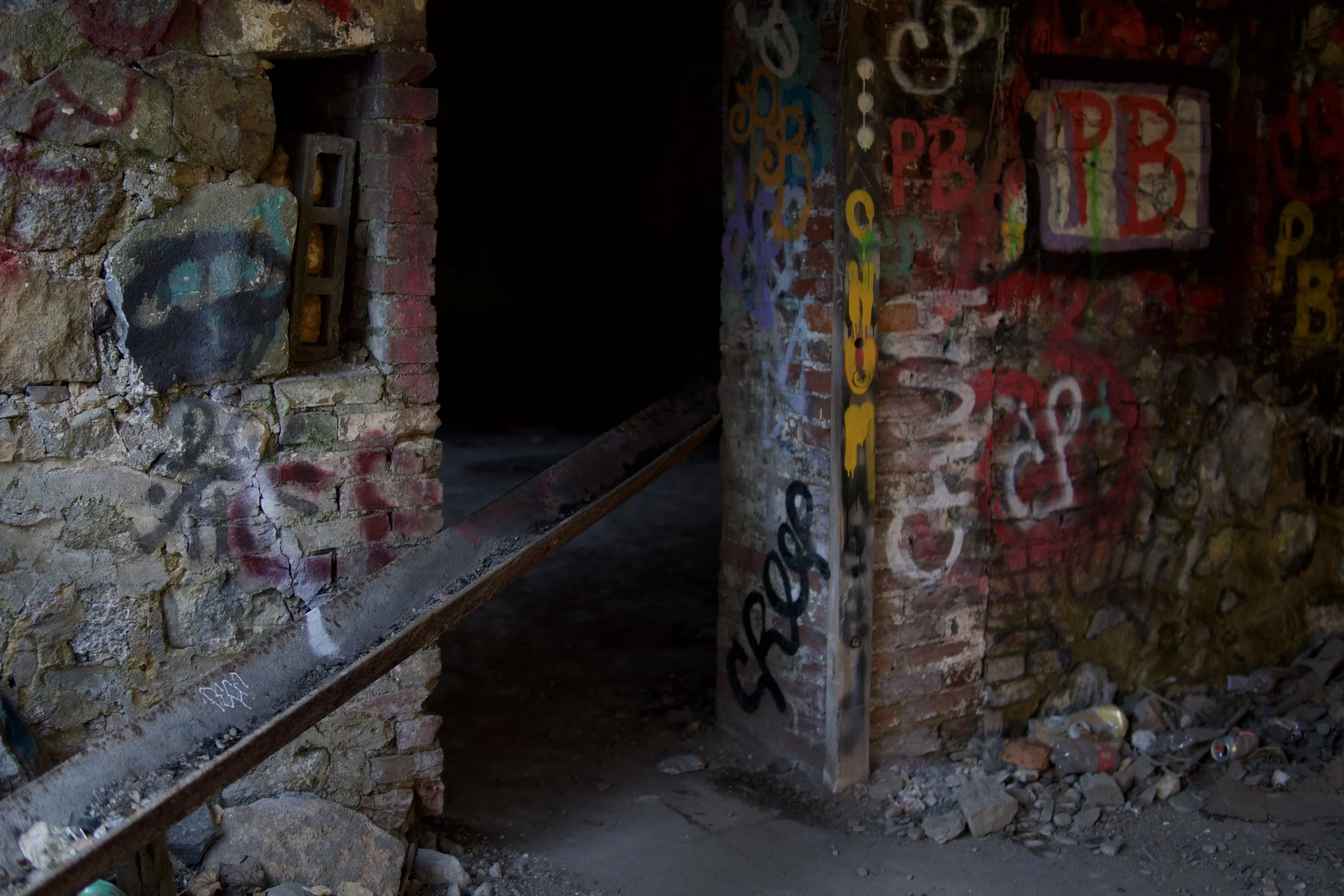 Interior of an abandoned brick building with graffiti on the walls.