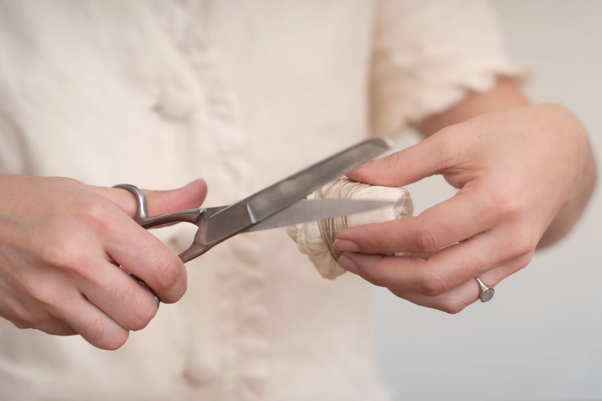 Person using scissors to cut a bundle of twine or string.
