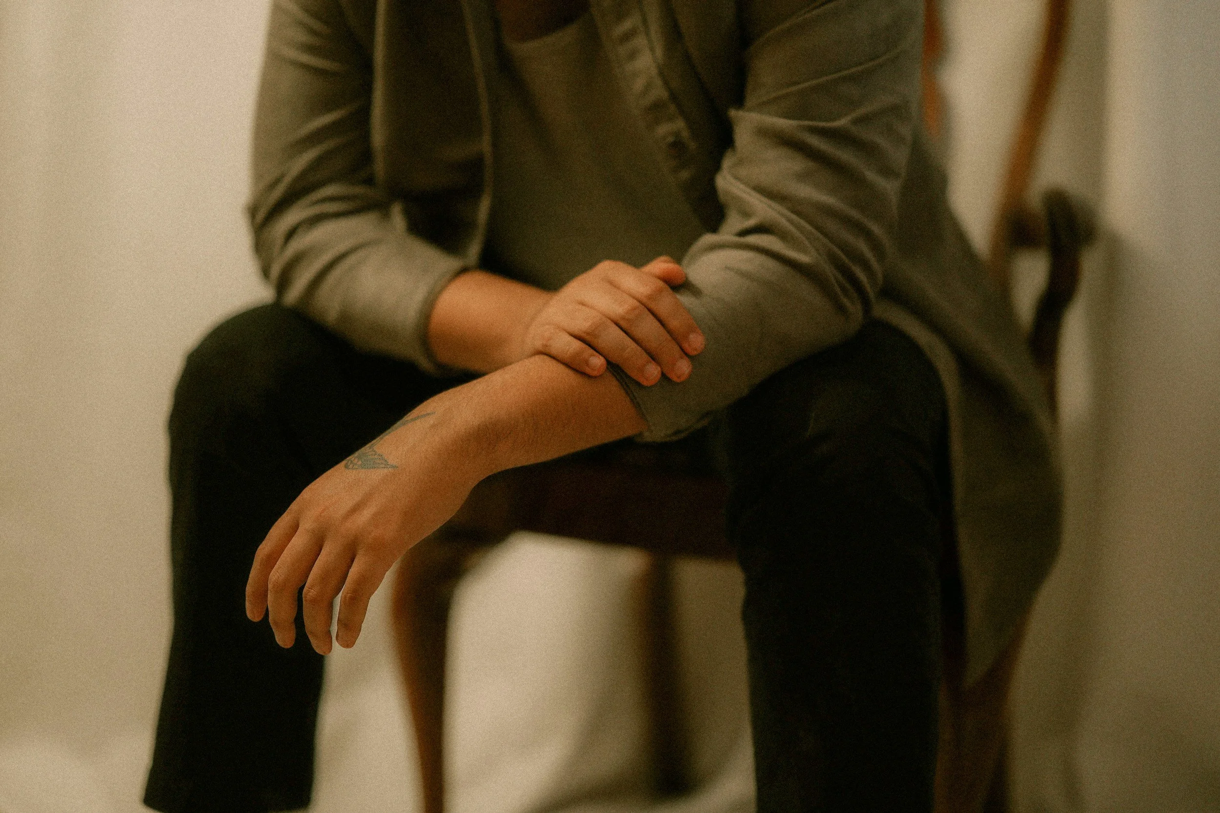 Close-up of a seated person resting their hands on their lap.