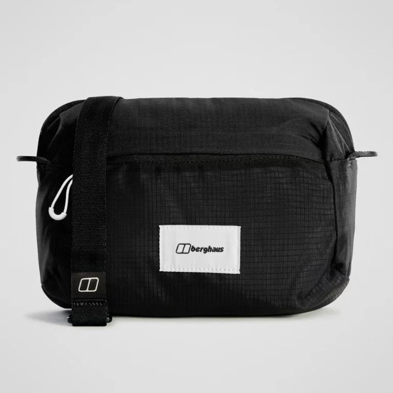Black Berghaus shoulder bag with front zipper pocket and branded white label, set against a plain background.