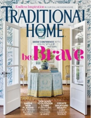 Cover of a magazine titled 'Traditional Home' featuring an open door leading to a sunlit room with a round table, two chairs, and large windows with curtains.