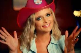 Young woman smiling, wearing a pink cowboy hat, in a festive indoor setting.