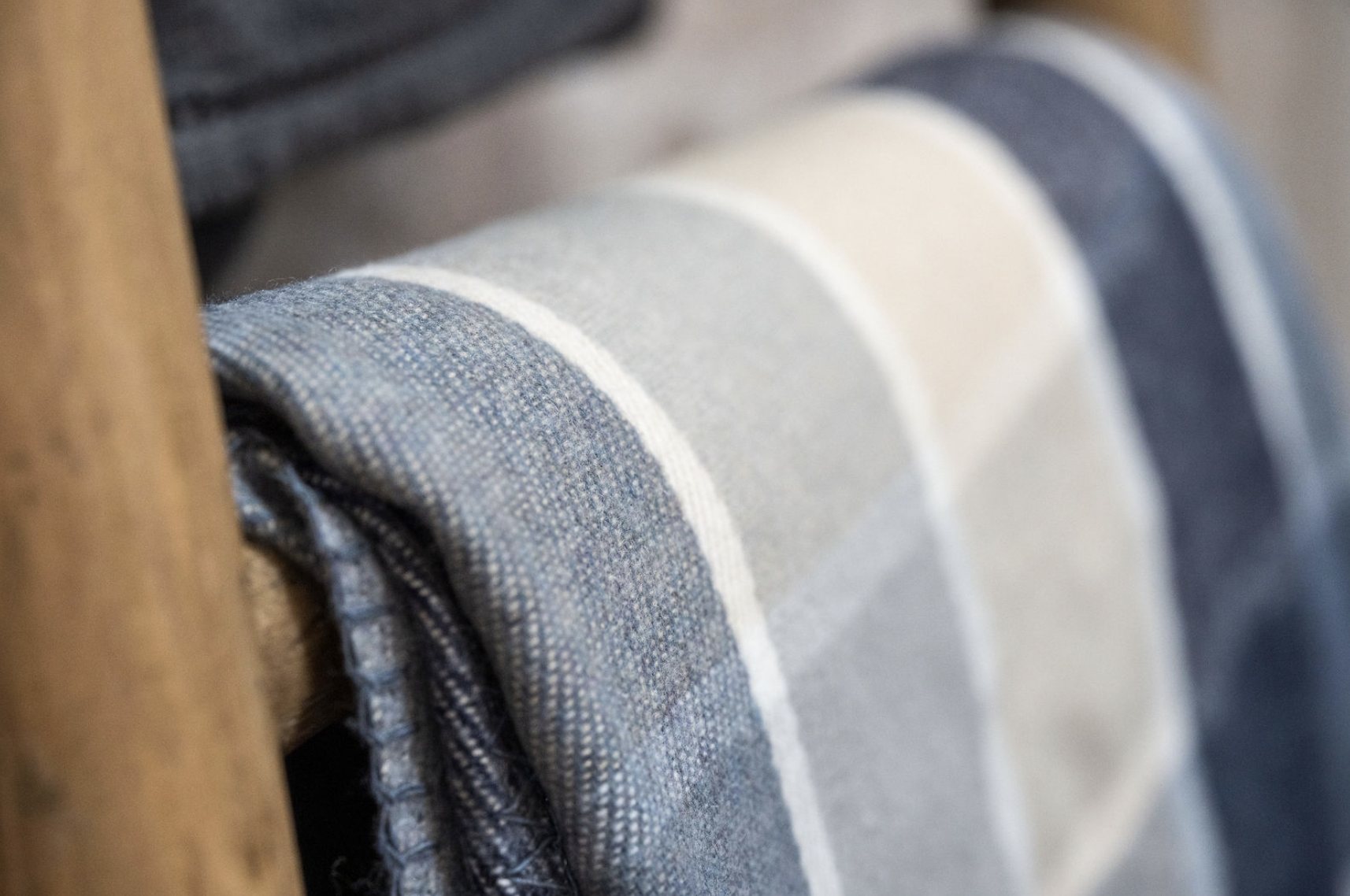 Close-up of folded denim fabric in light and dark shades on a wooden surface.