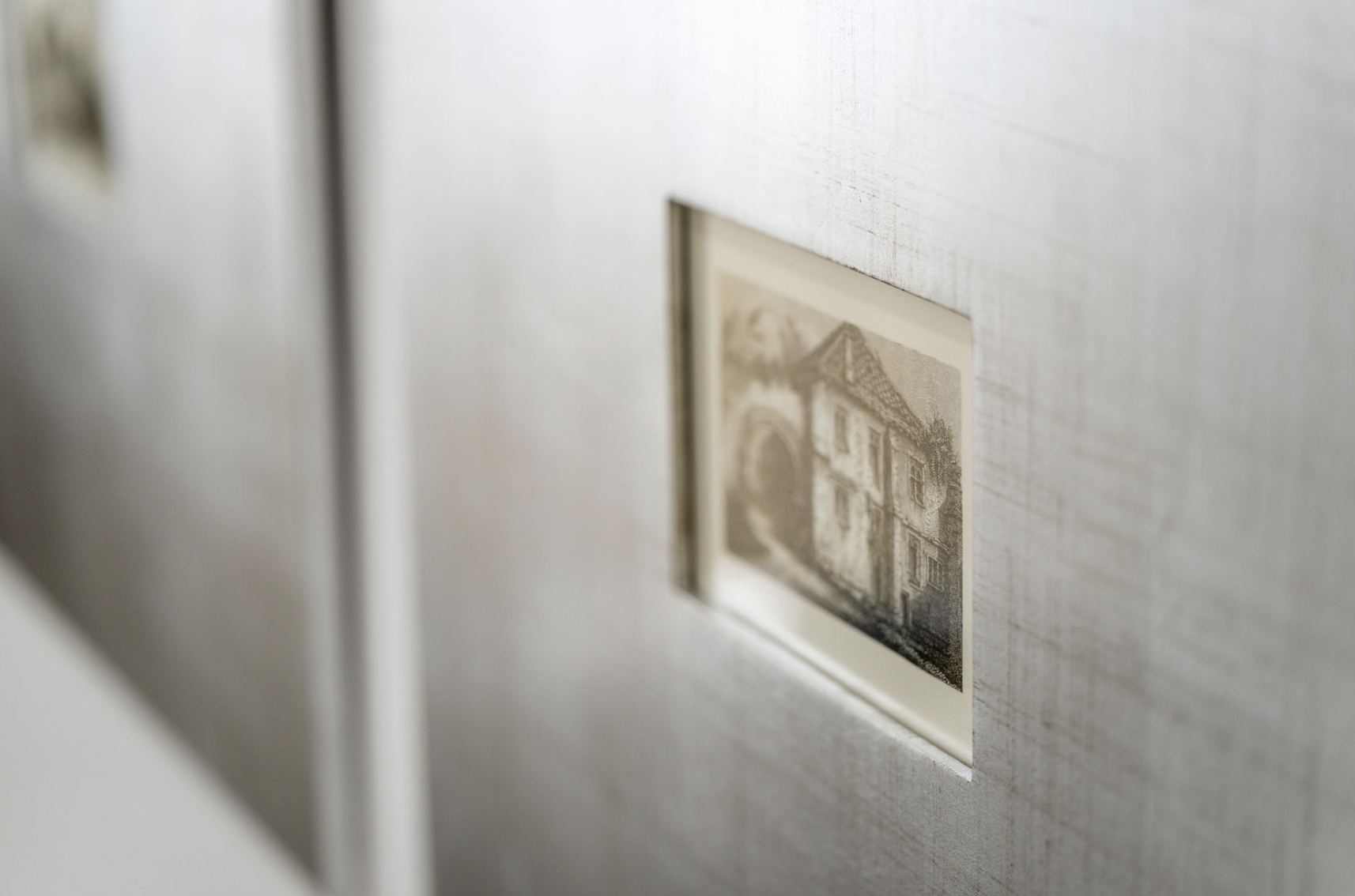 Close-up of a wall with a small, embedded black-and-white photograph of a house.