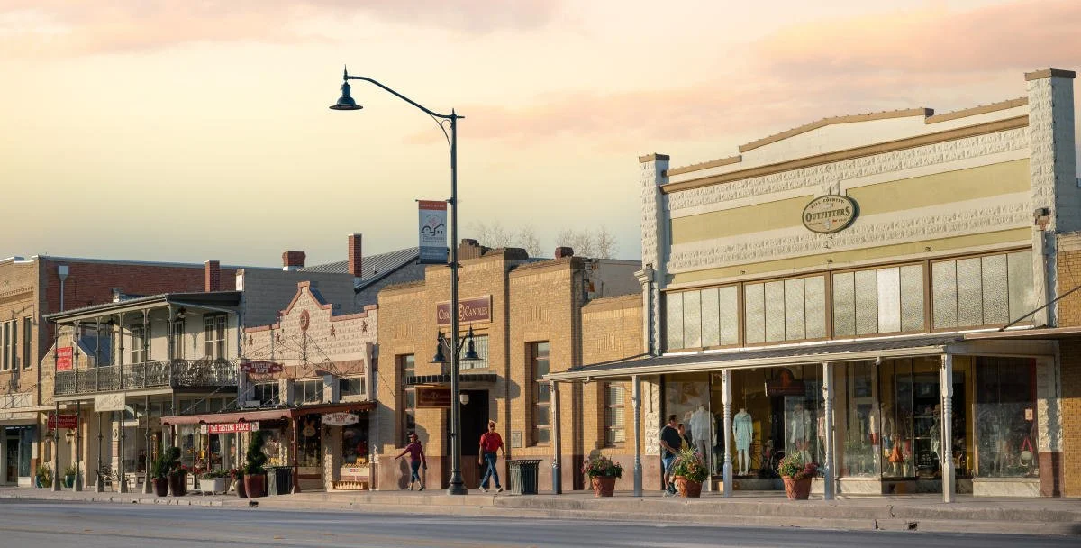 Street view of shops and storefronts in a small town with a clear sky during sunset.