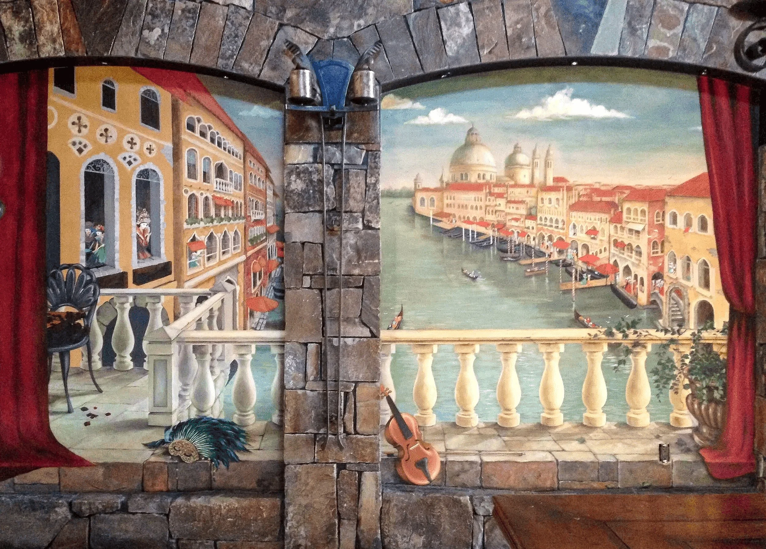 A painted mural depicting a scenic canal view in Venice, Italy, framed by a stone fireplace or archway with a balcony and musical instruments.