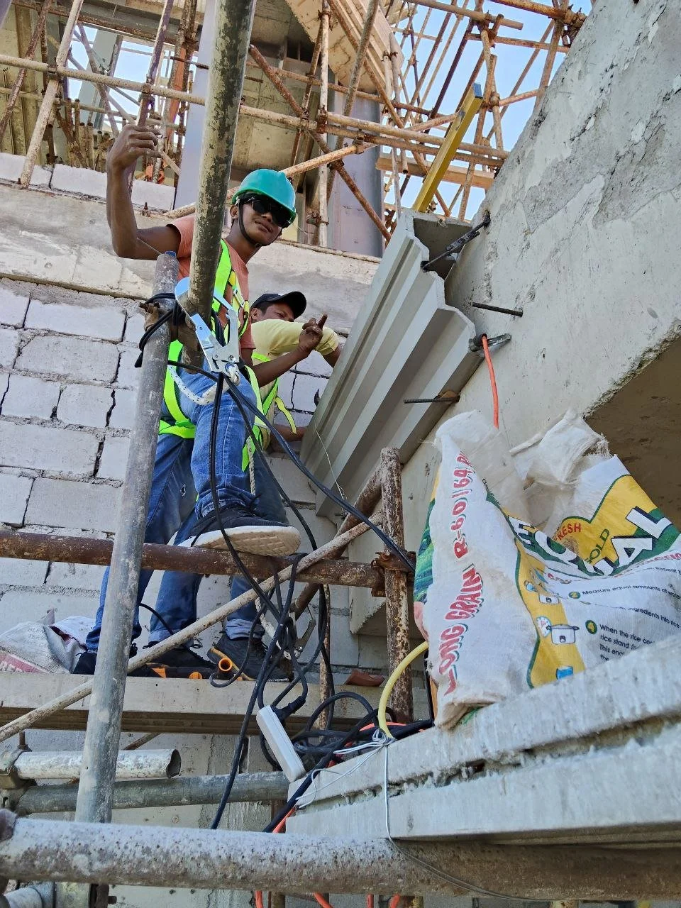 Two mathanog precast workers on scaffolding working on precast and installation on a concrete building.