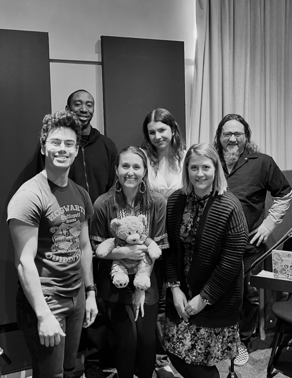 A black and white cast photo from inside a recording studio.