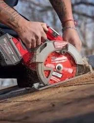 Guernsey Handyman using a Milwaukee red and black circular saw to cut a piece of wood outdoors.