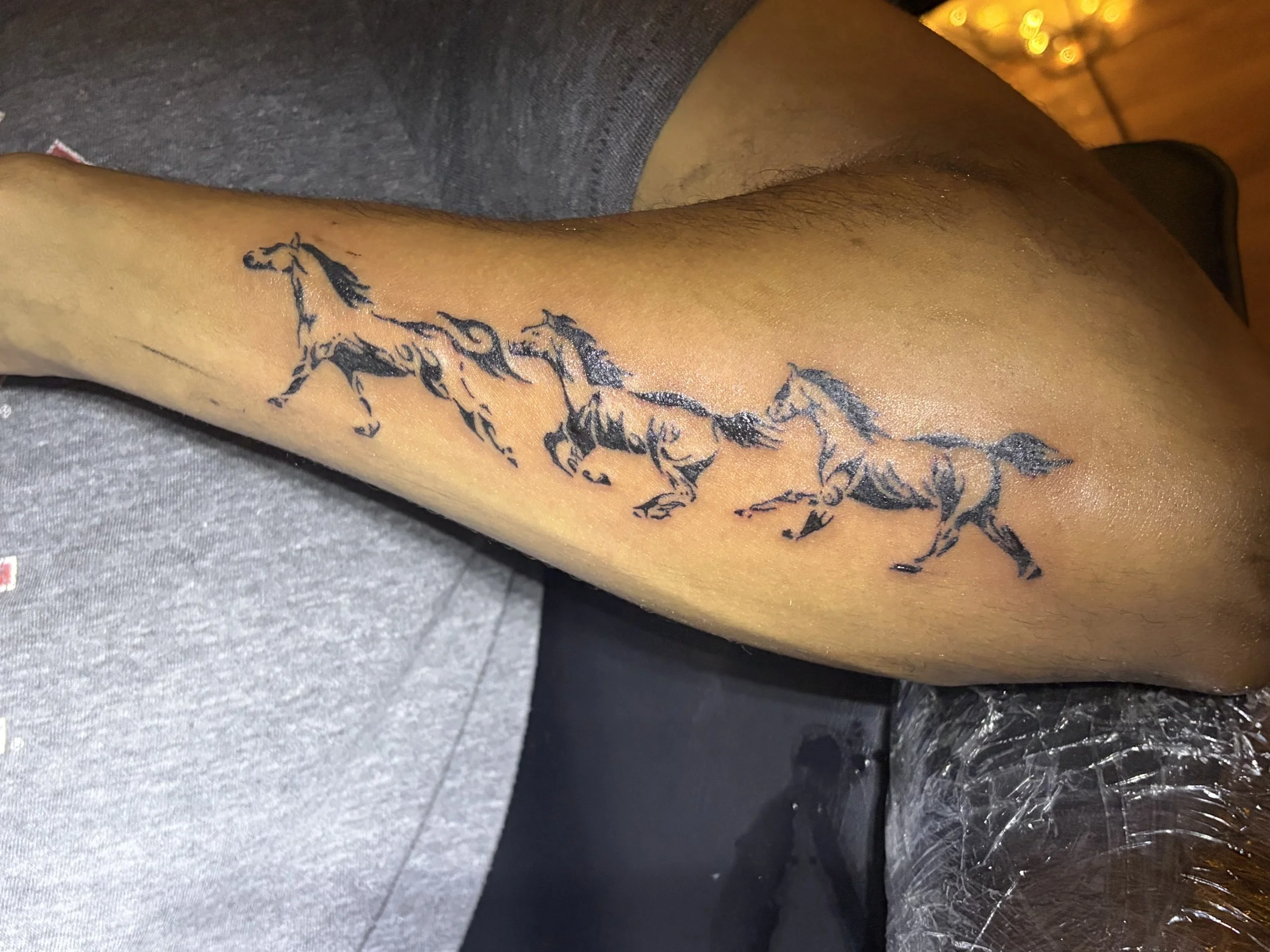A tattoo of a horse on a person's lower leg, with a cloudy background and some hair on the leg.
