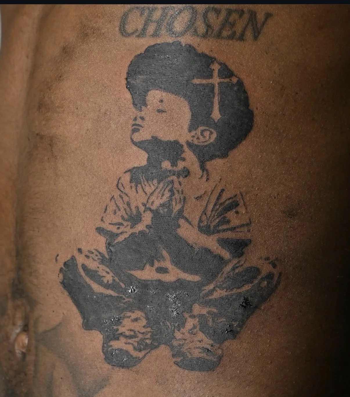 Tattoo of a young girl with a cross in her hair, with the words 'CHOSEN' above her.