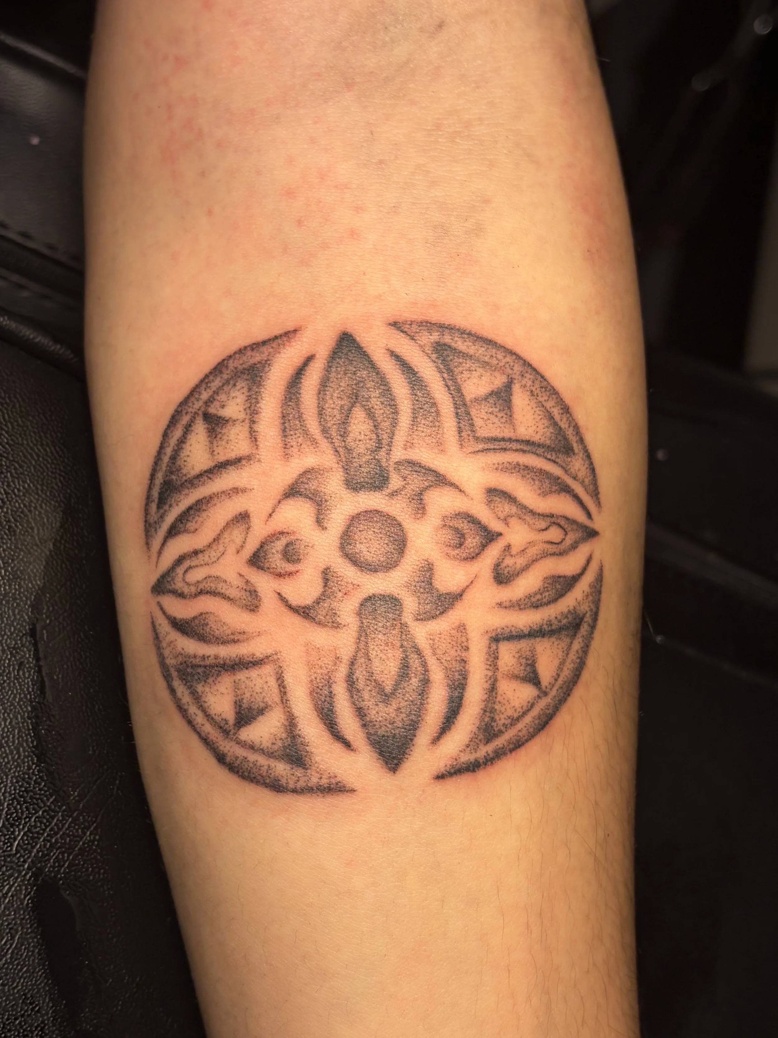 Tattoo of a tribal-style design on a person's arm.